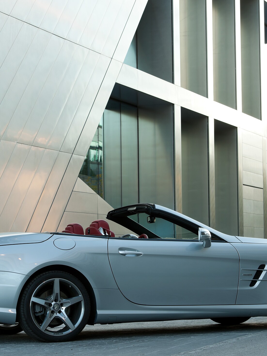 Ein Mercedes-AMG Cabriolet vor einem futuristischen Gebäude.