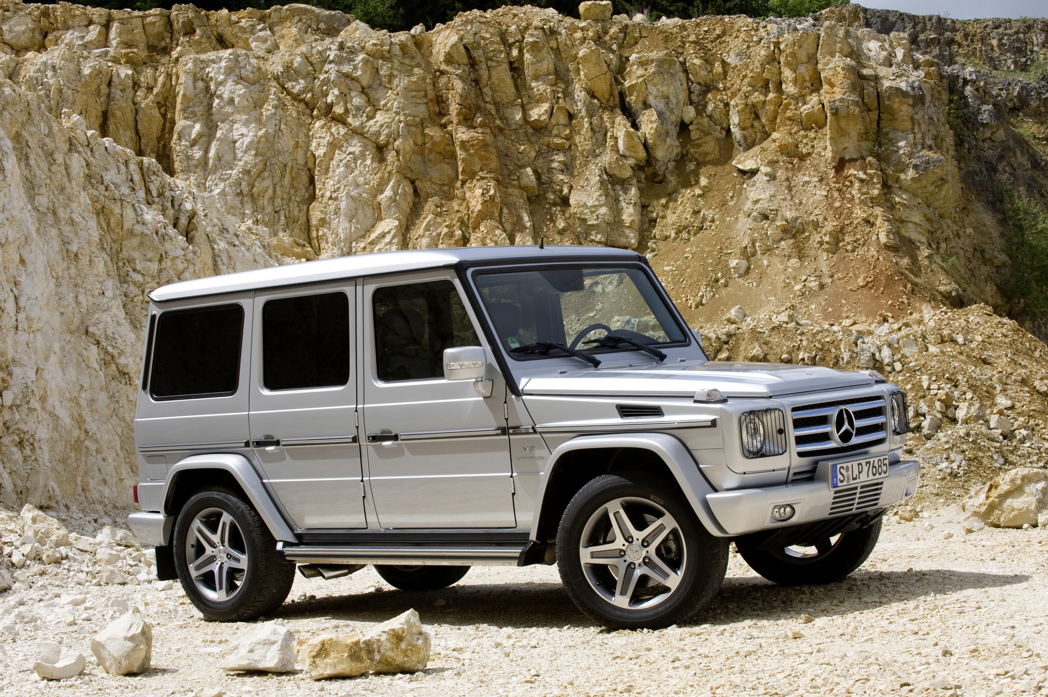 Service- und Garantiepakete | Mercedes-Benz. Eine silberne G-Klasse von Mercedes-Benz steht in der Sonne vor einer Felswand.