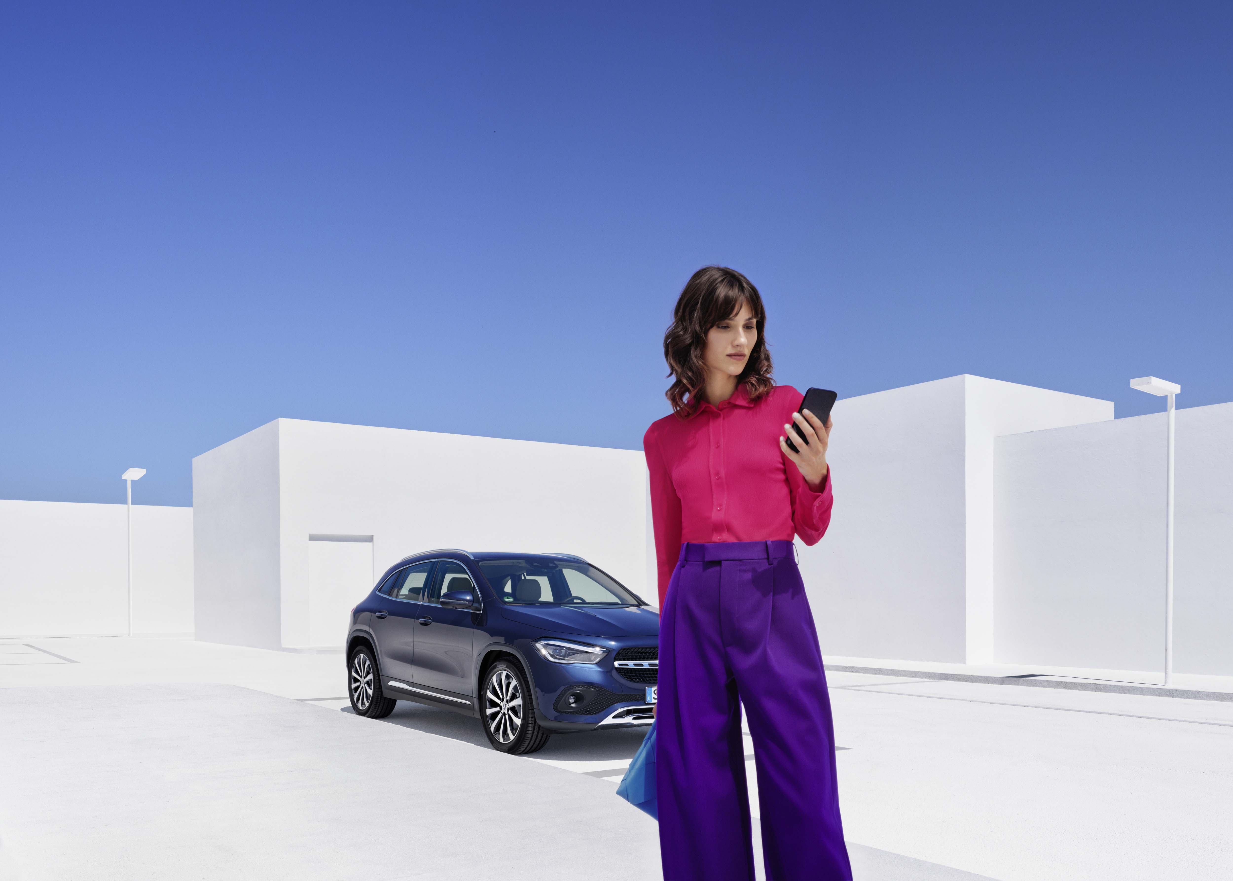 Garantie-Paket | Mercedes-Benz Frau mit Handy in der Hand vor einem Mercedes-Benz.