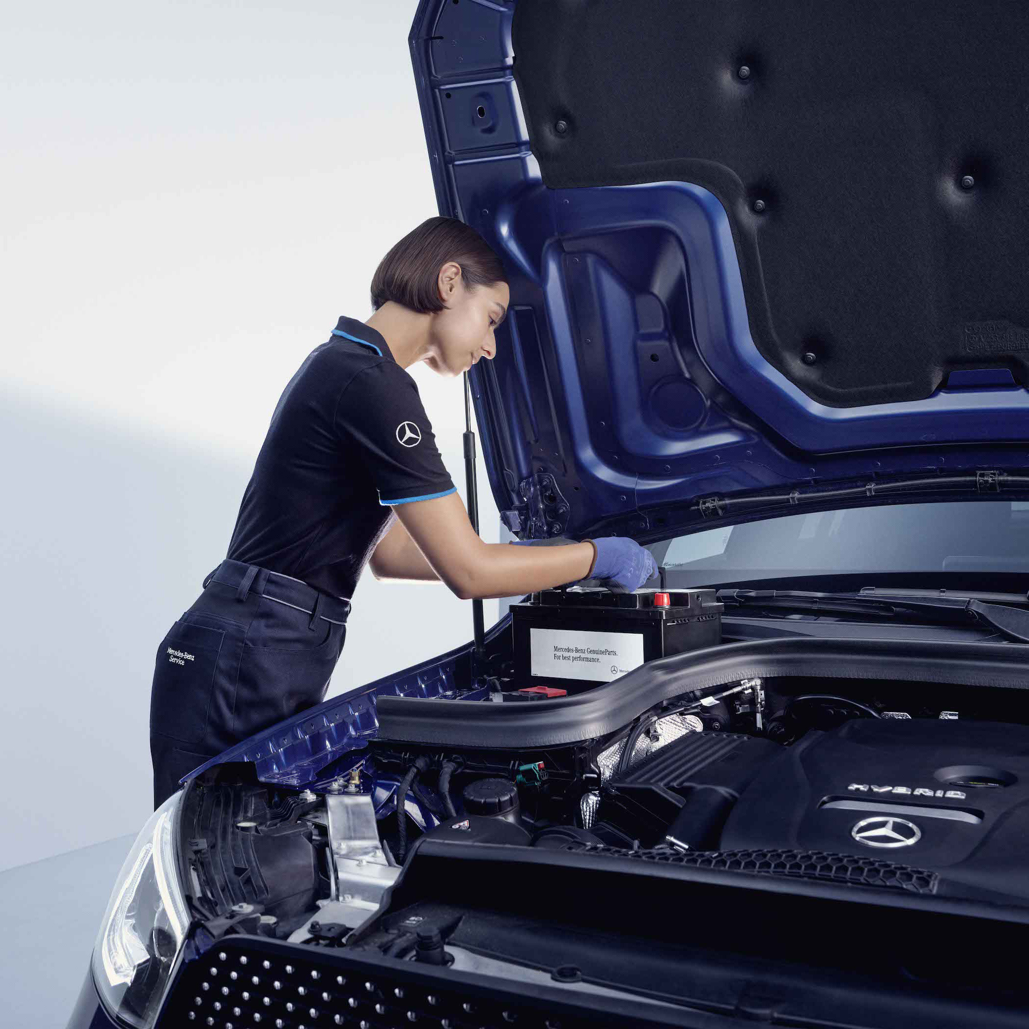 Original-Teile | Mercedes-Benz Ein Automechaniker beugt sich über die geöffnete Motorhaube eines Mercedes-Benz.