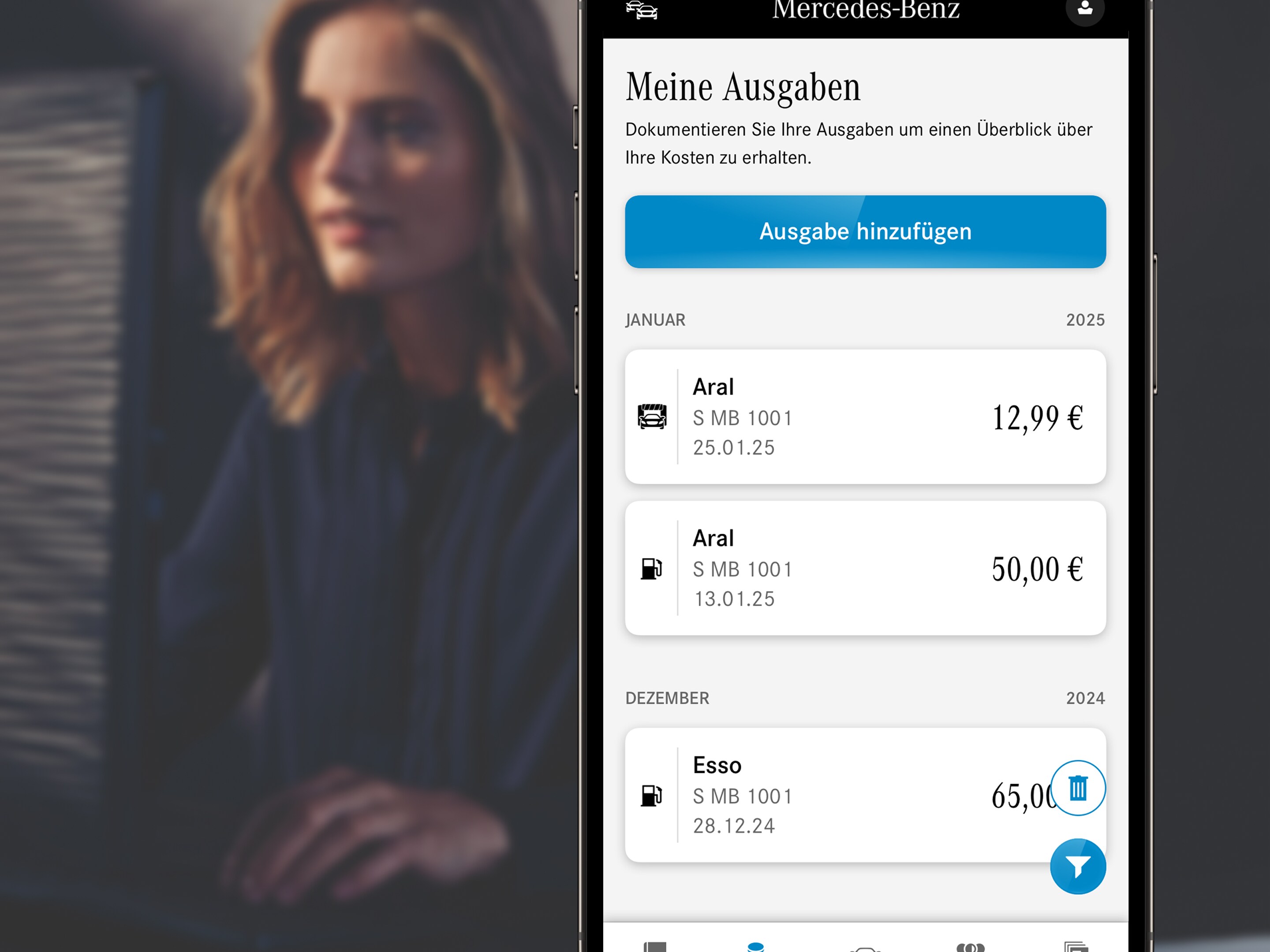 Eine Frau in einem dunklen Outfit verschwommen im Hintergrund, im Vordergrund ein Handy, welches das Mercedes-Benz Fahrtenbuch als App zeigt.