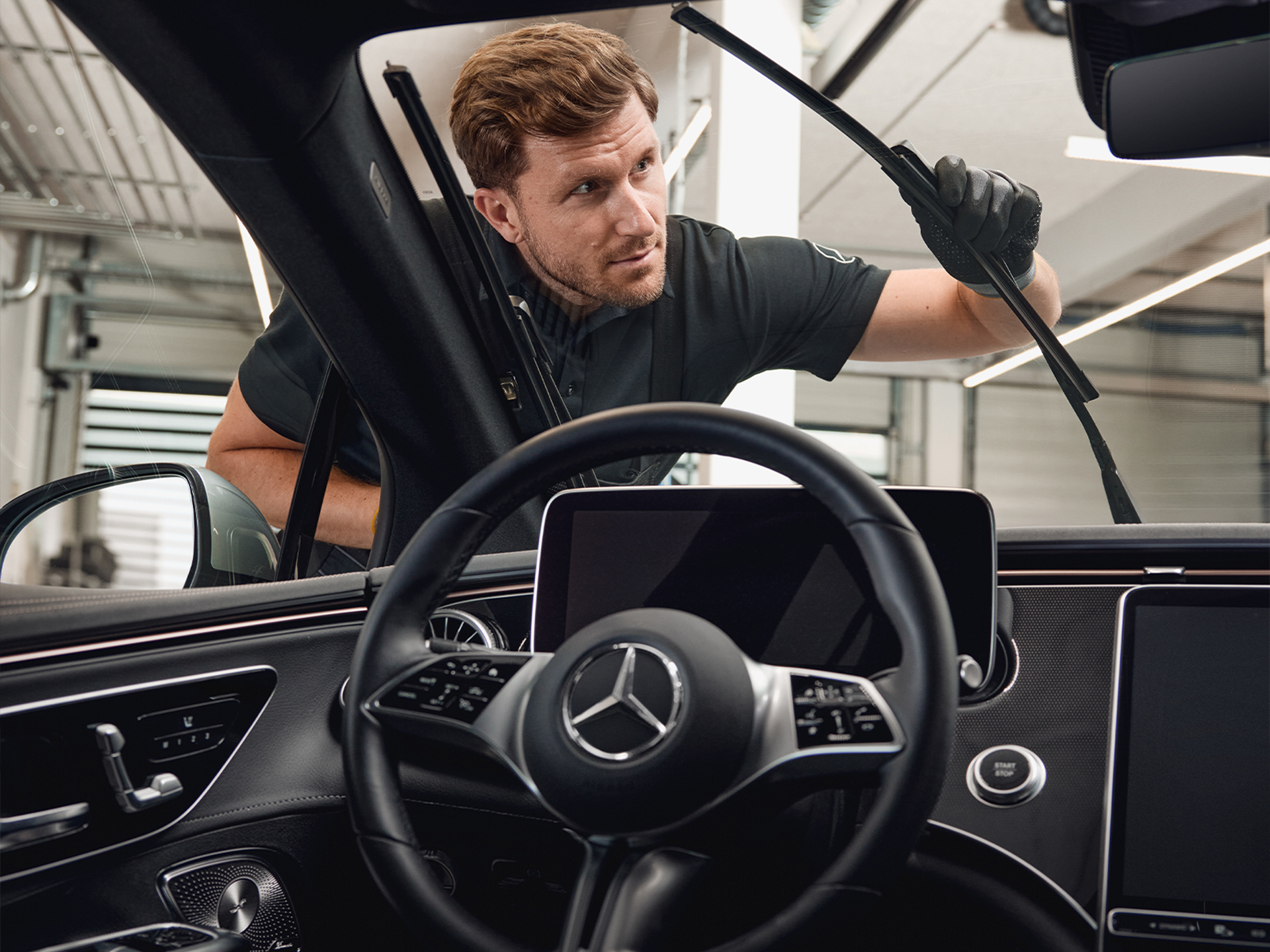 Herbstaktion | Mercedes-Benz Ein Mercedes-Benz Mechaniker in Arbeitskleidung und Handschuhen beim Ersetzen der Wischblätter.
