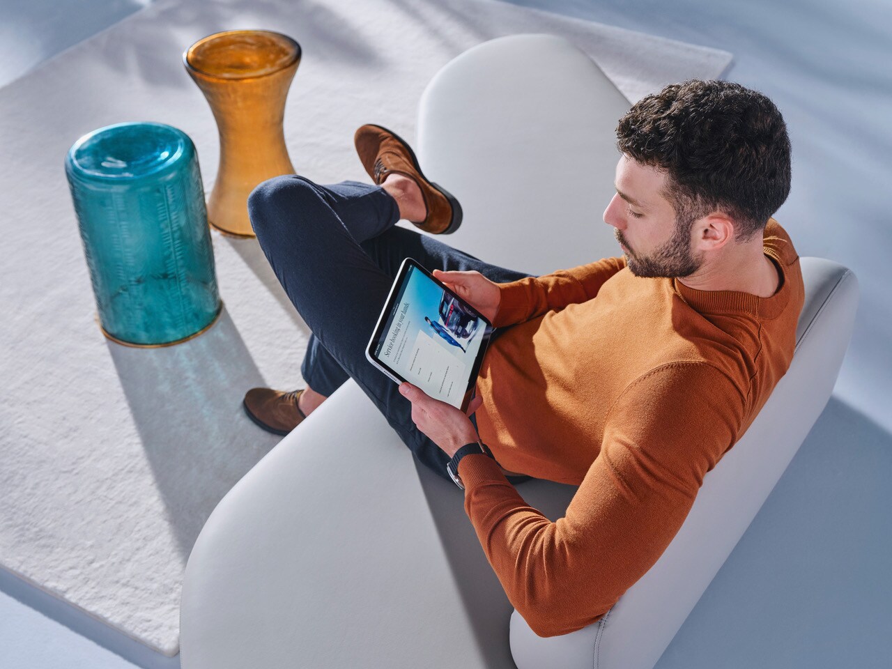 EIn Mann sitzt auf einem Stuhl und hälft ein Tablet in der Handy