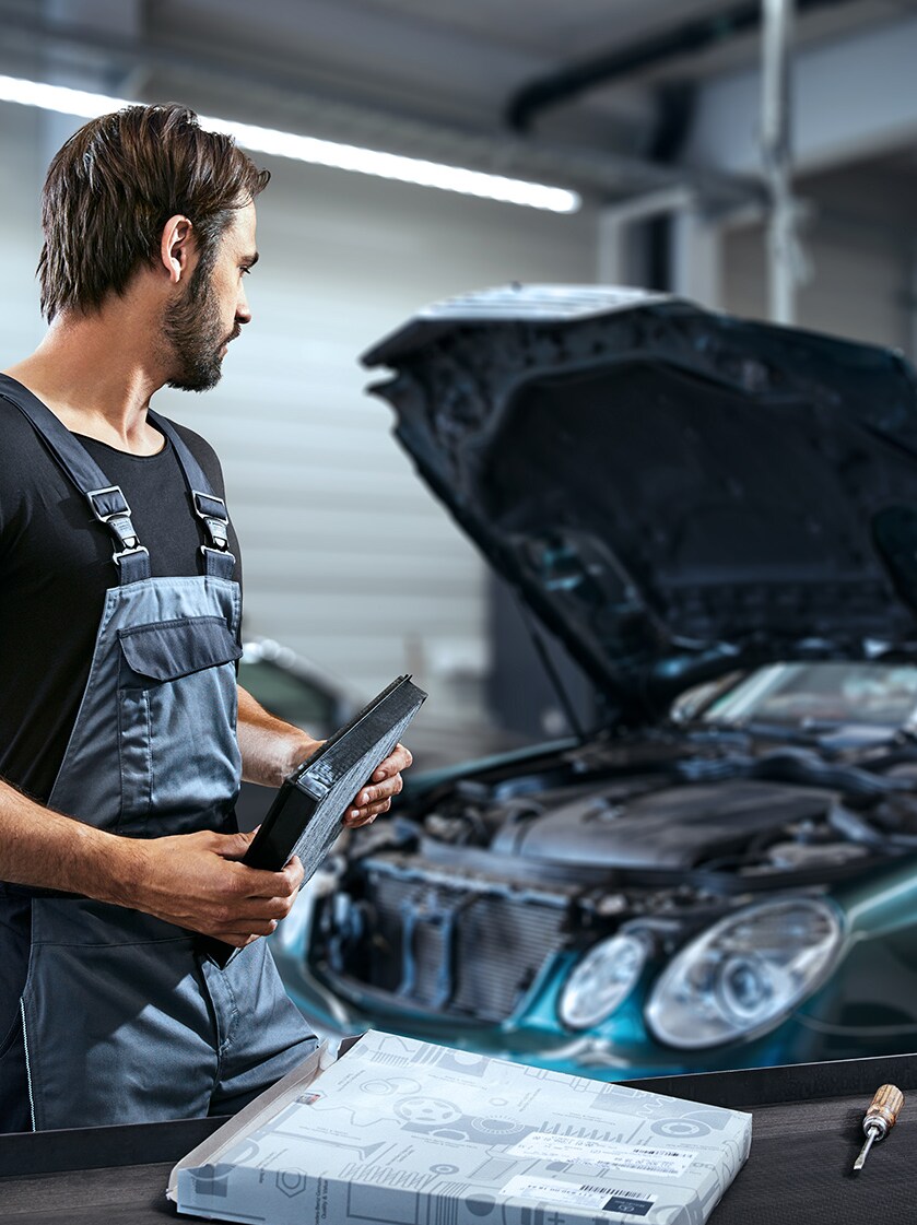 Ein Mann arbeitet an einer geöffneten Motorhaube.