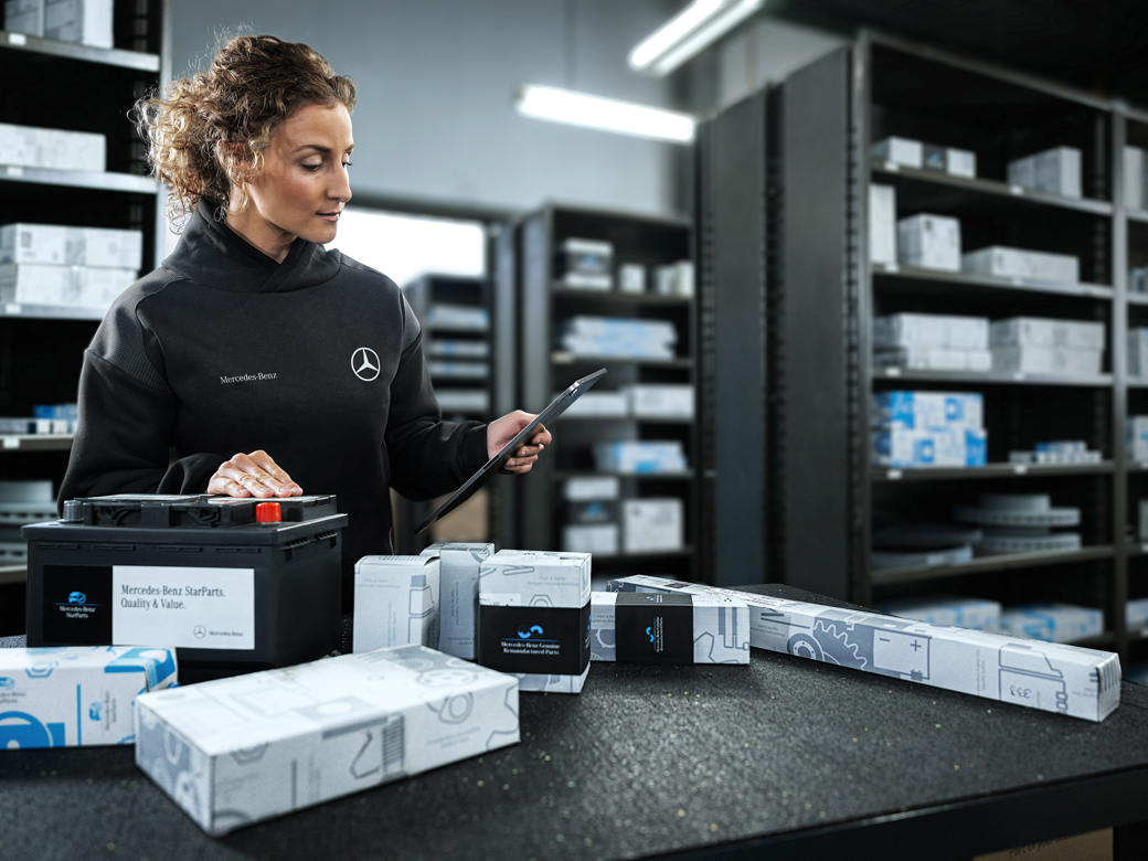 PARTSpro+ | Mercedes-Benz. Eine Frau packt verschiedene Teile als Paket.