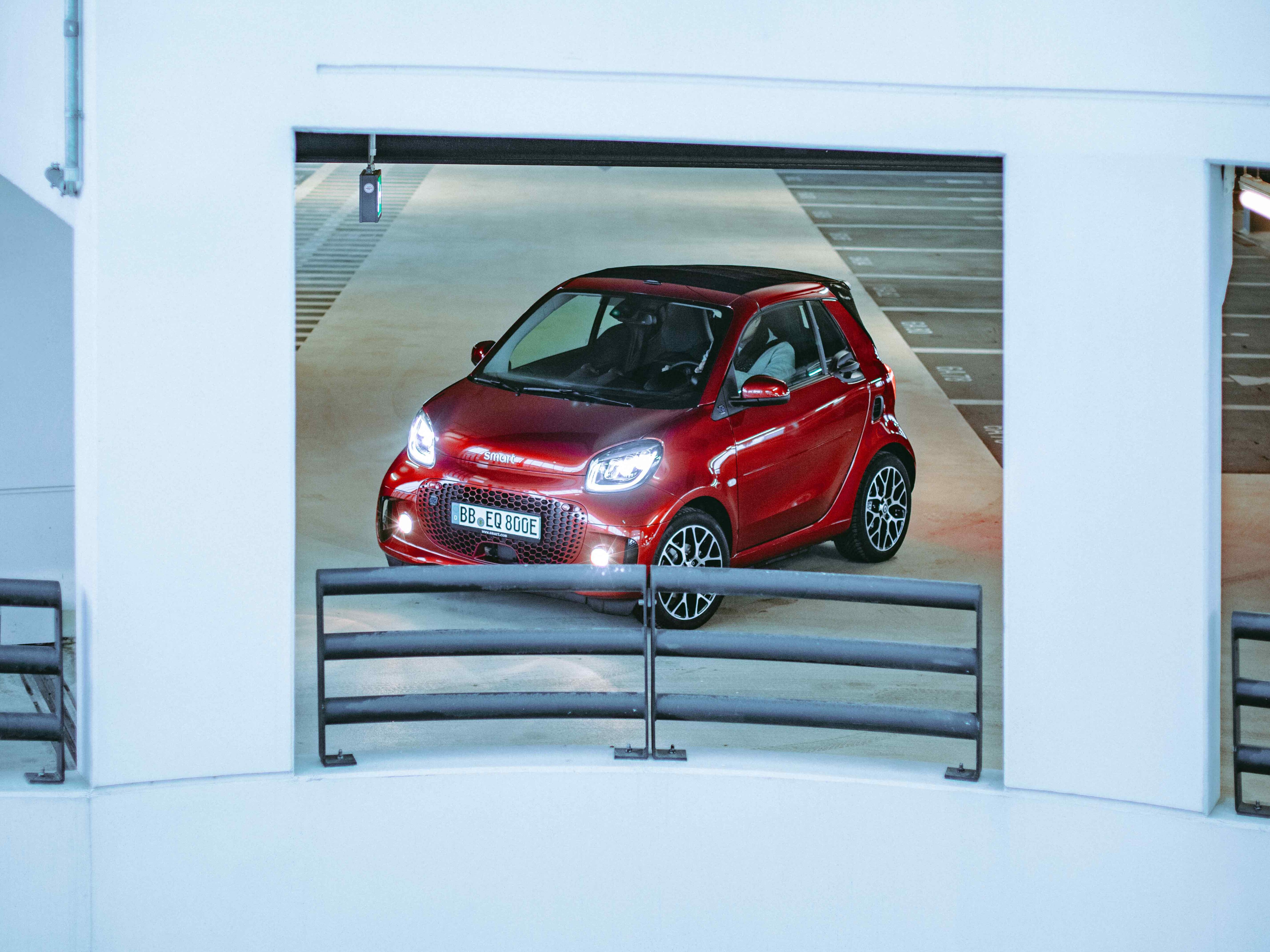 Ein roter smart steht in einem Parkhaus.