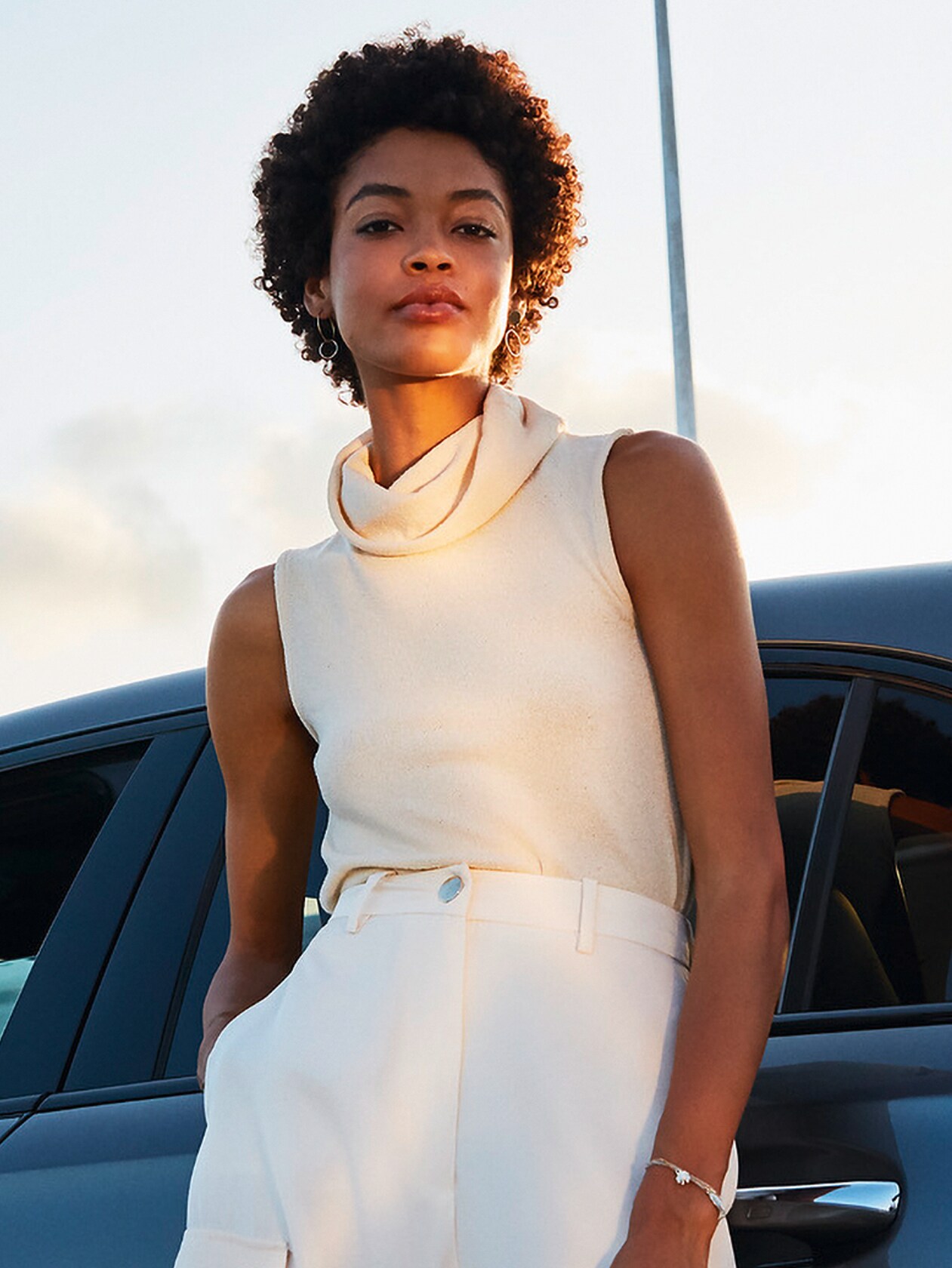 Blonde Frau vor rotem Mercedes.