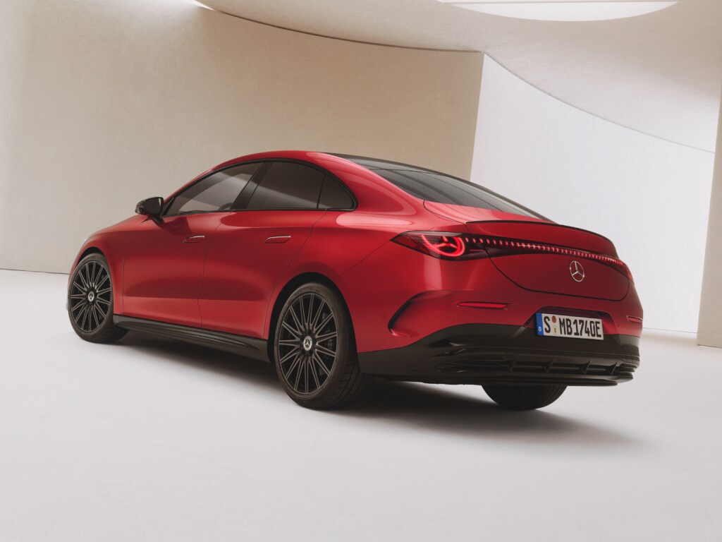 Seitliche Heckansicht eines roten elektrischer Mercedes-Benz CLA, der in einer hellen lichtdurchfluteten Halle steht.
