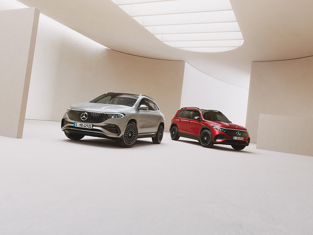 Elektroauto Förderungen | Mercedes-Benz. Ein silberner und ein roter vollelektrischer Mercedes-Benz steht auf hellem Untergrund in einer lichtdurchflutenden Halle.