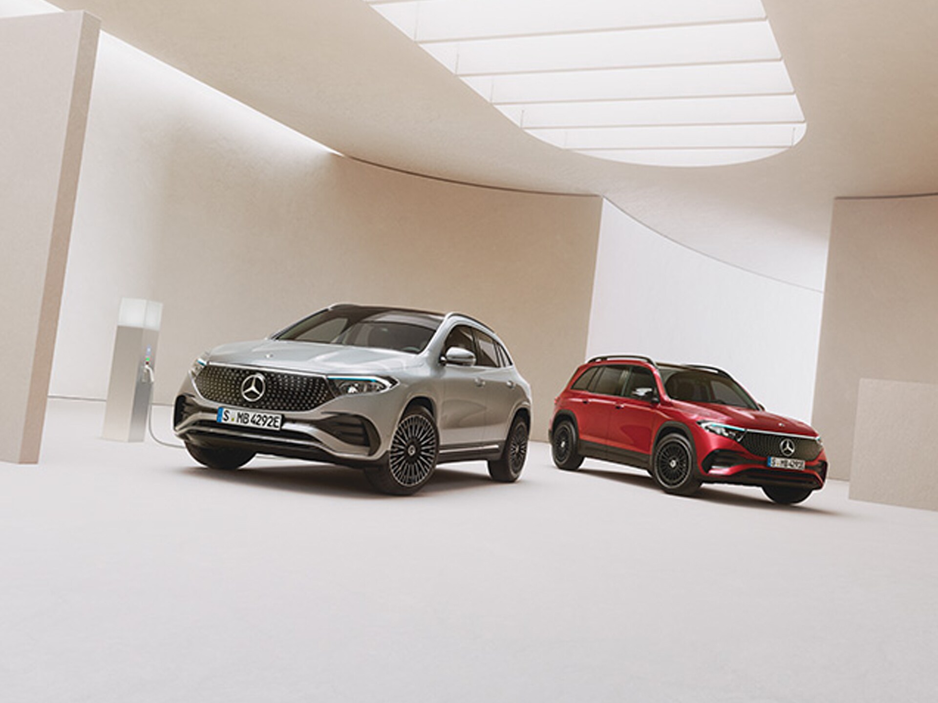 Frontansicht von zwei weißen vollelektrischer Mercedes-Benz, der an einer Ladesäule steht und aufgeladen wird.