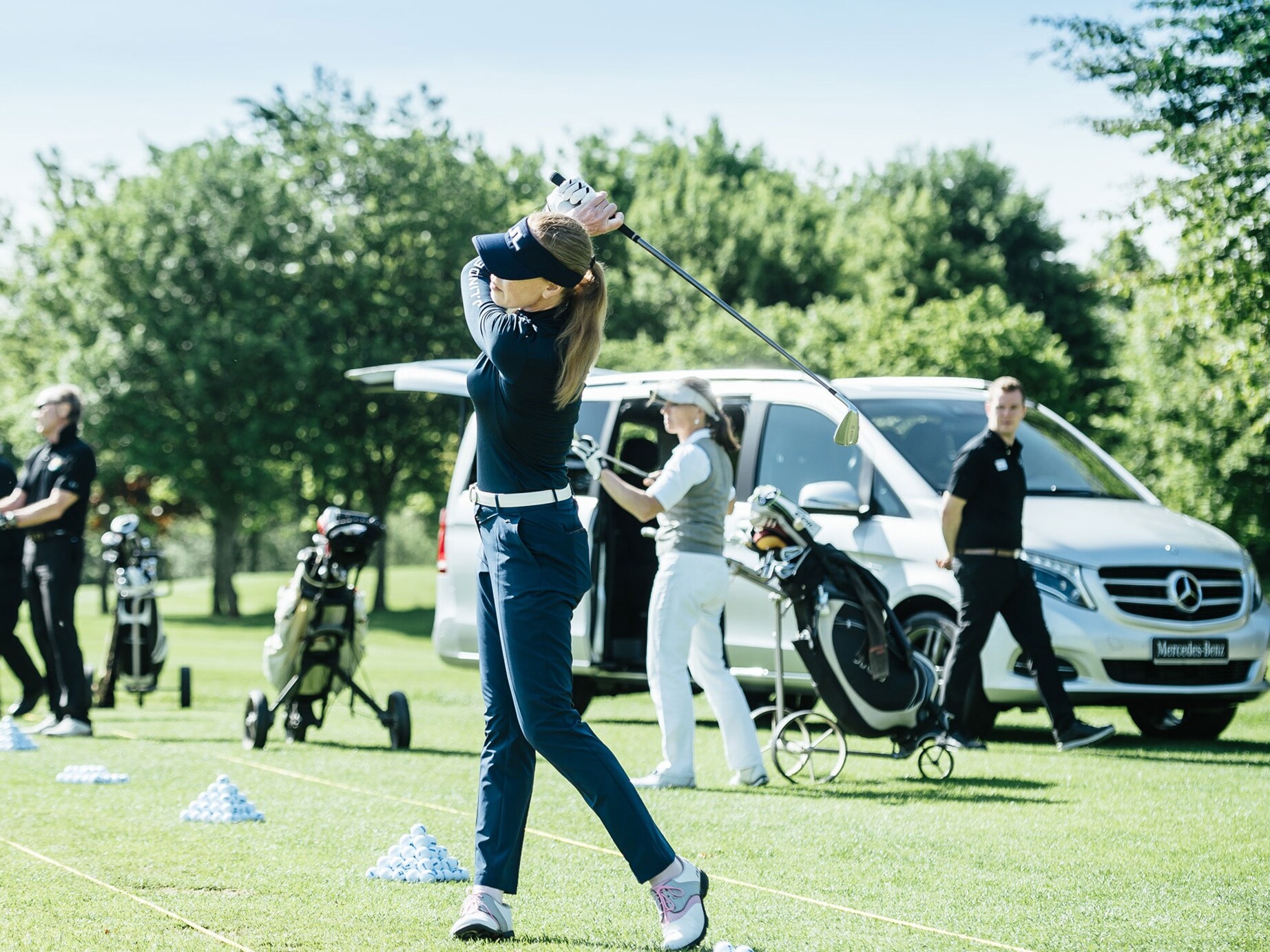 Ein Golfspielerin schlägt einen Ball übers Feld. Eine Menschenmenge schaut dabei zu.