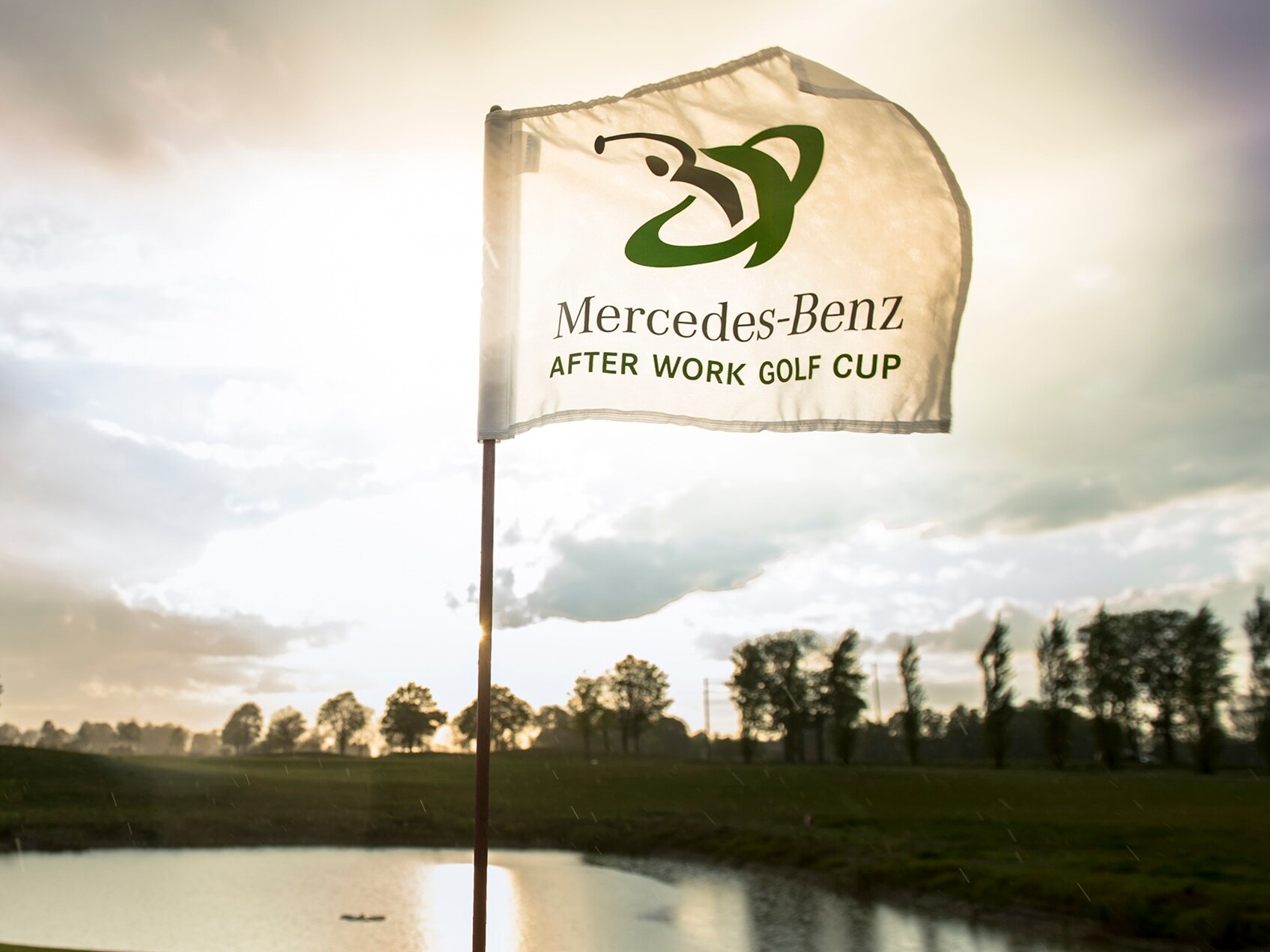 Ein Golfplatz mit einer wehenden Fahne im Sonnenlicht.