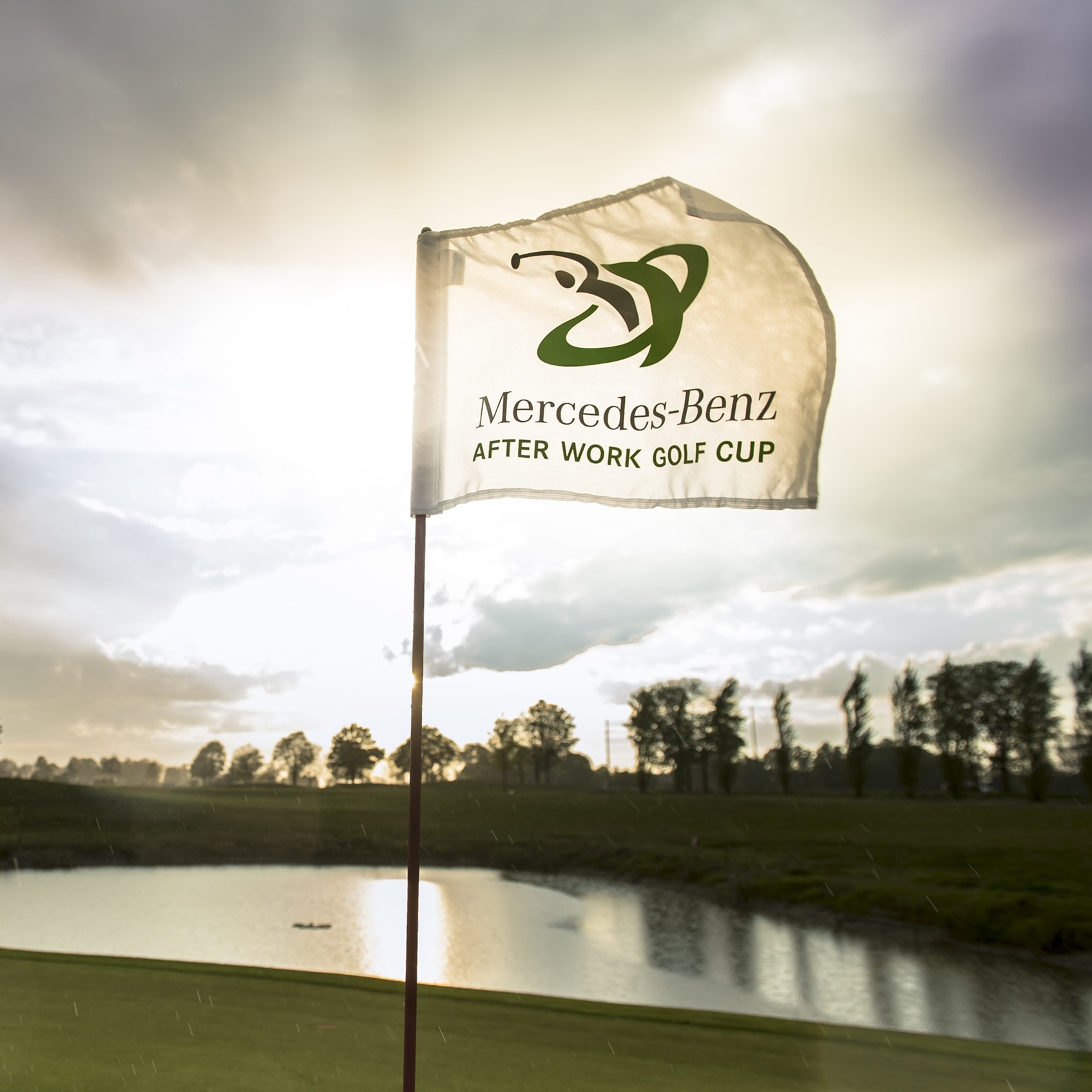 Golf | Mercedes-Benz Ein Golfplatz mit einer wehenden Fahne im Sonnenlicht.