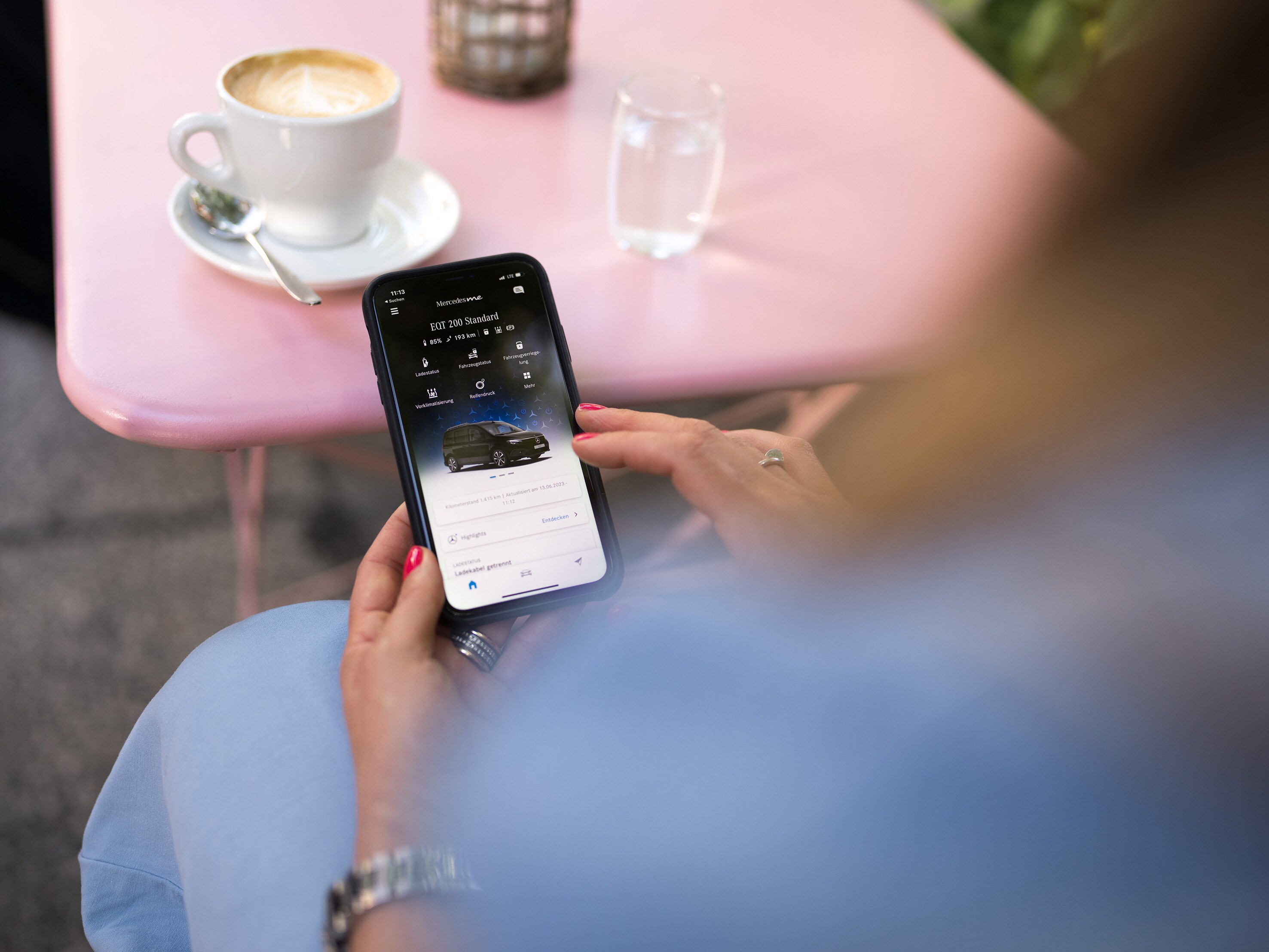 Eine Frau sitzt an einem Smartphone und konfiguriert ein Fahrzeug von Mercedes-Benz.