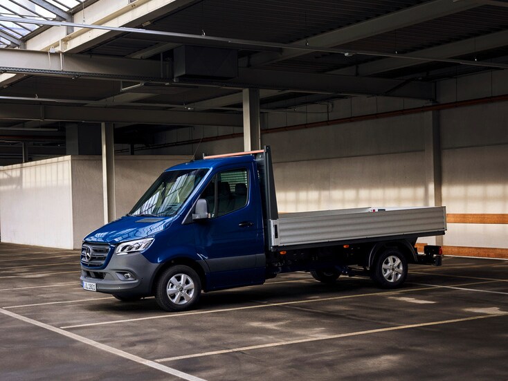 Ein blauer Mercedes-Benz Sprinter Pritschenwagen steht auf einem Stellplatz in einer Lagerhalle.