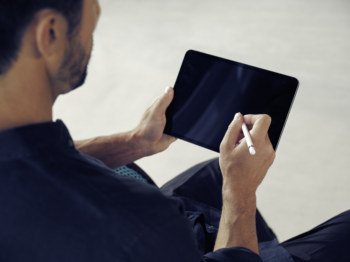 Ein Mann tippt mit einem Stift auf sein Tablet.