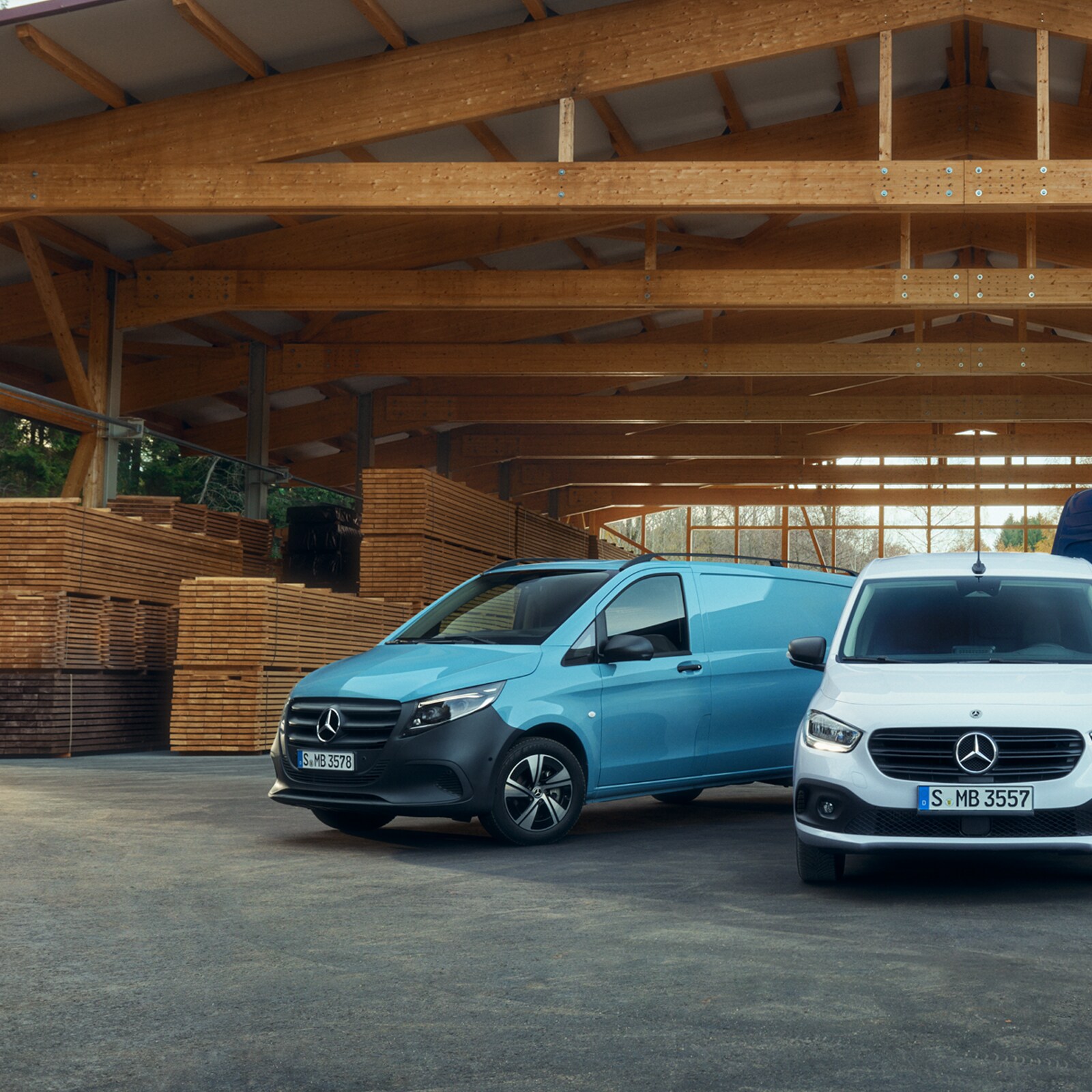 Sprinter-, Vito- und Citan Kastenwagen parkend unter einem Holzdach vor Holzpaletten