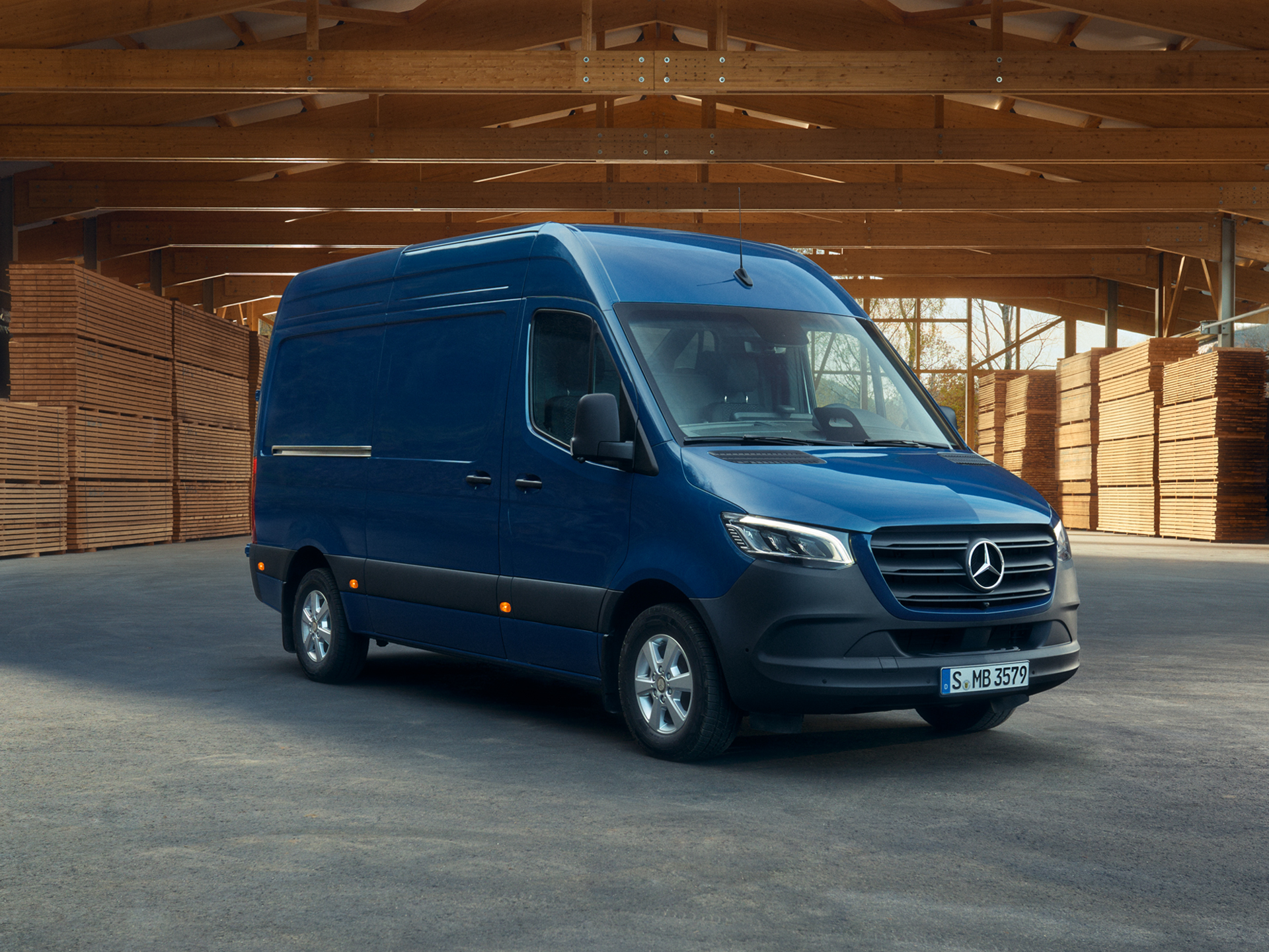 Transporter Highlights | Mercedes-Benz Ein blauer Mercedes-Benz Sprinter Kastenwagen, parkend vor Holzpaletten.