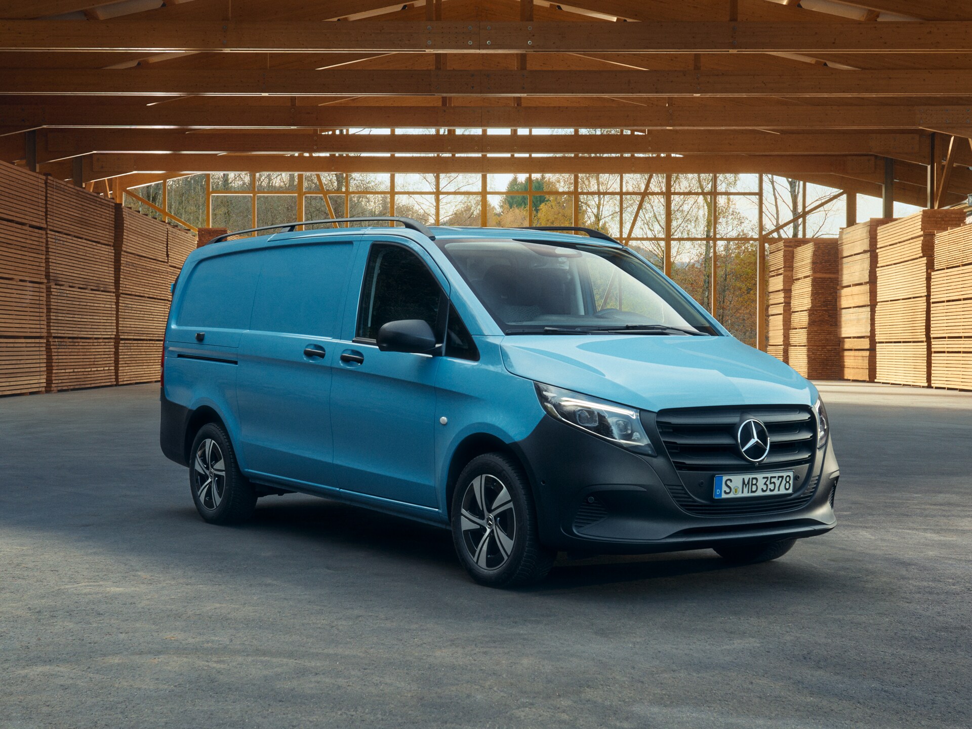 Ein hellblauer Mercedes-Benz Vito Kastenwagen, parkend vor Holzpaletten.