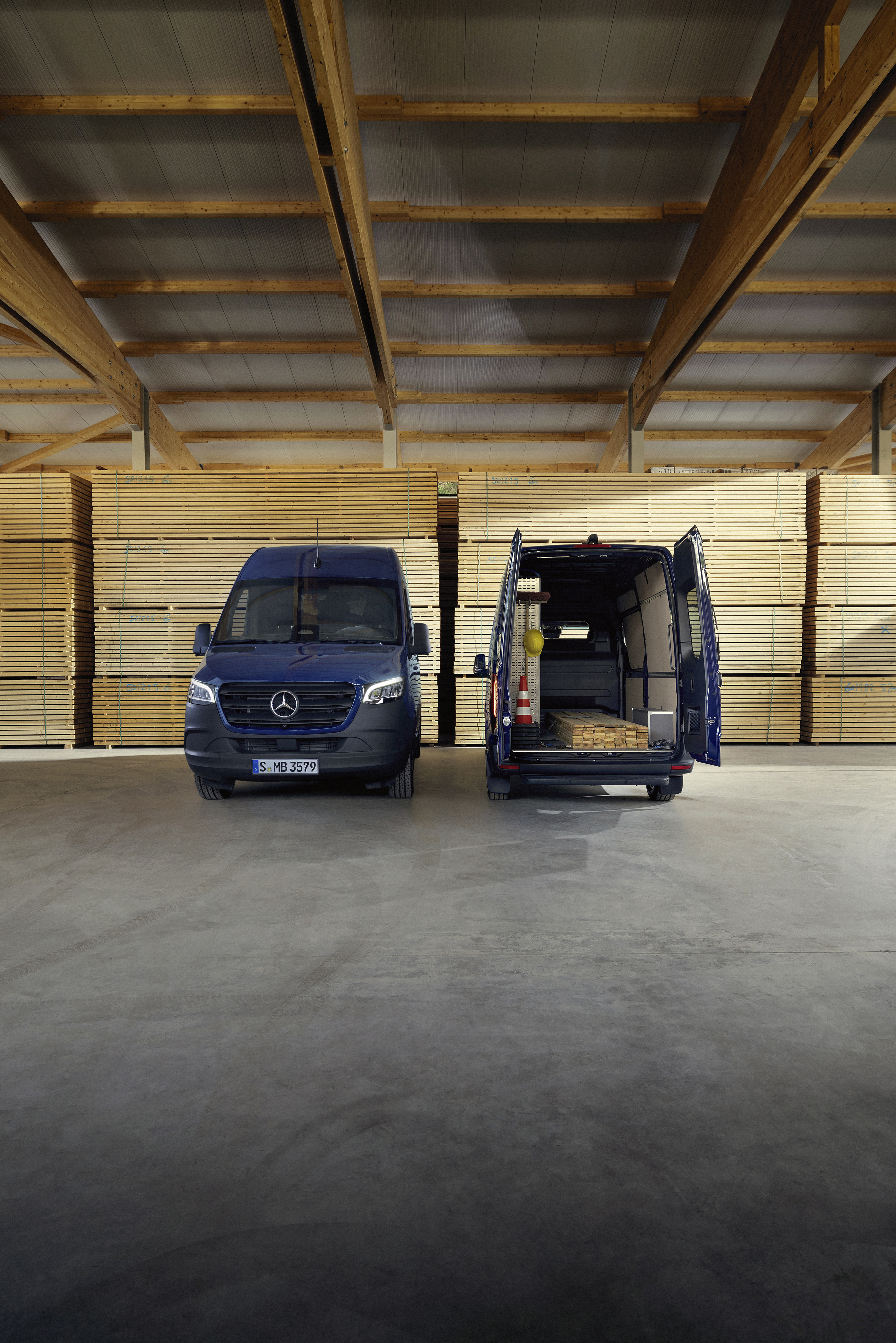 Transporter Highlights | Mercedes-Benz Ein blauer Mercedes-Benz Sprinter Kastenwagen, seitliche Ansicht, parkend vor Holzpaletten.
