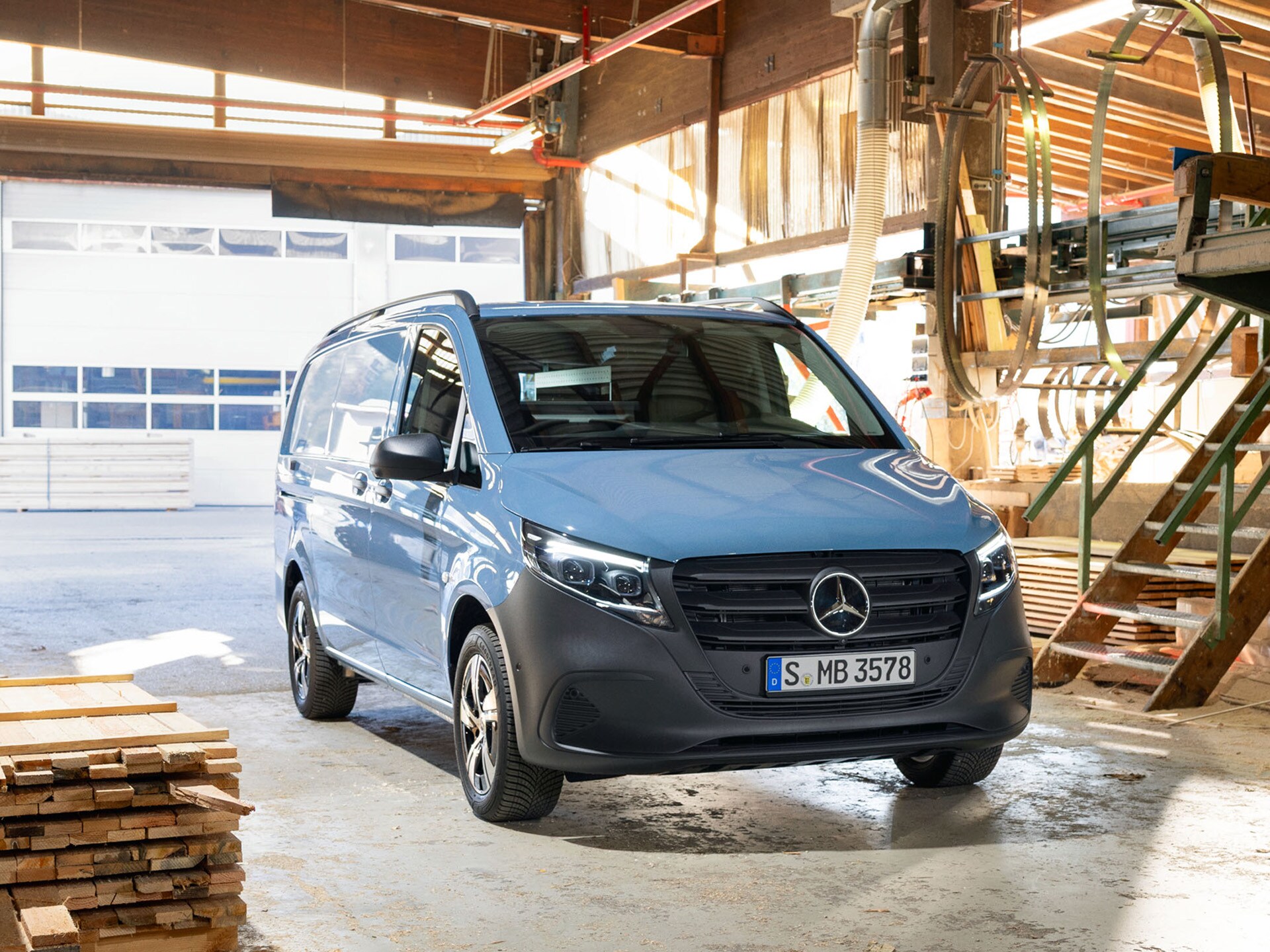 Ein hellblauer Mercedes-Benz Vito Kastenwagen, parkend vor Holzpaletten.