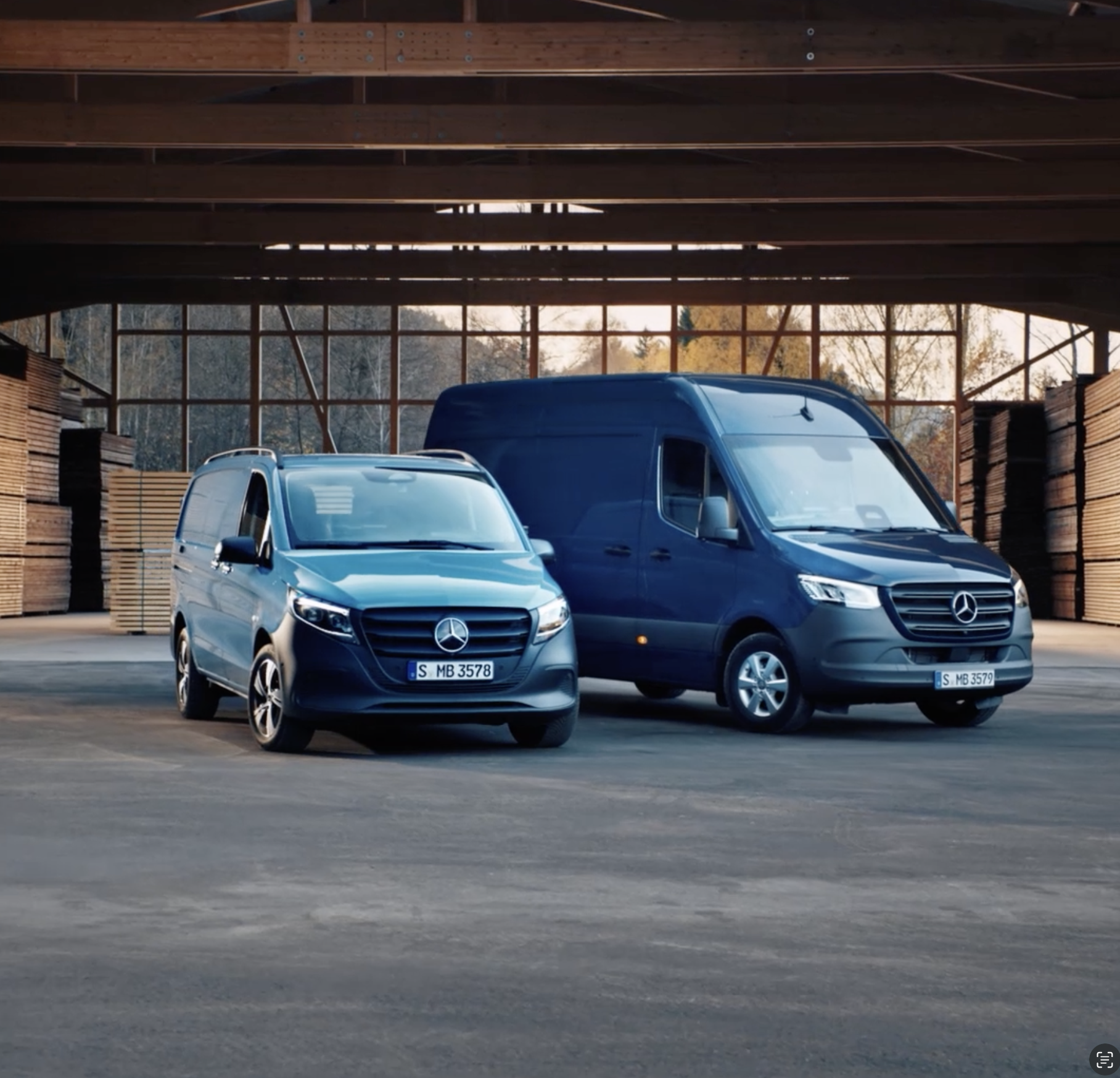 Zwei verschiedene Transportermodelle von Mercedes-Benz stehen in einer Lagerhalle.