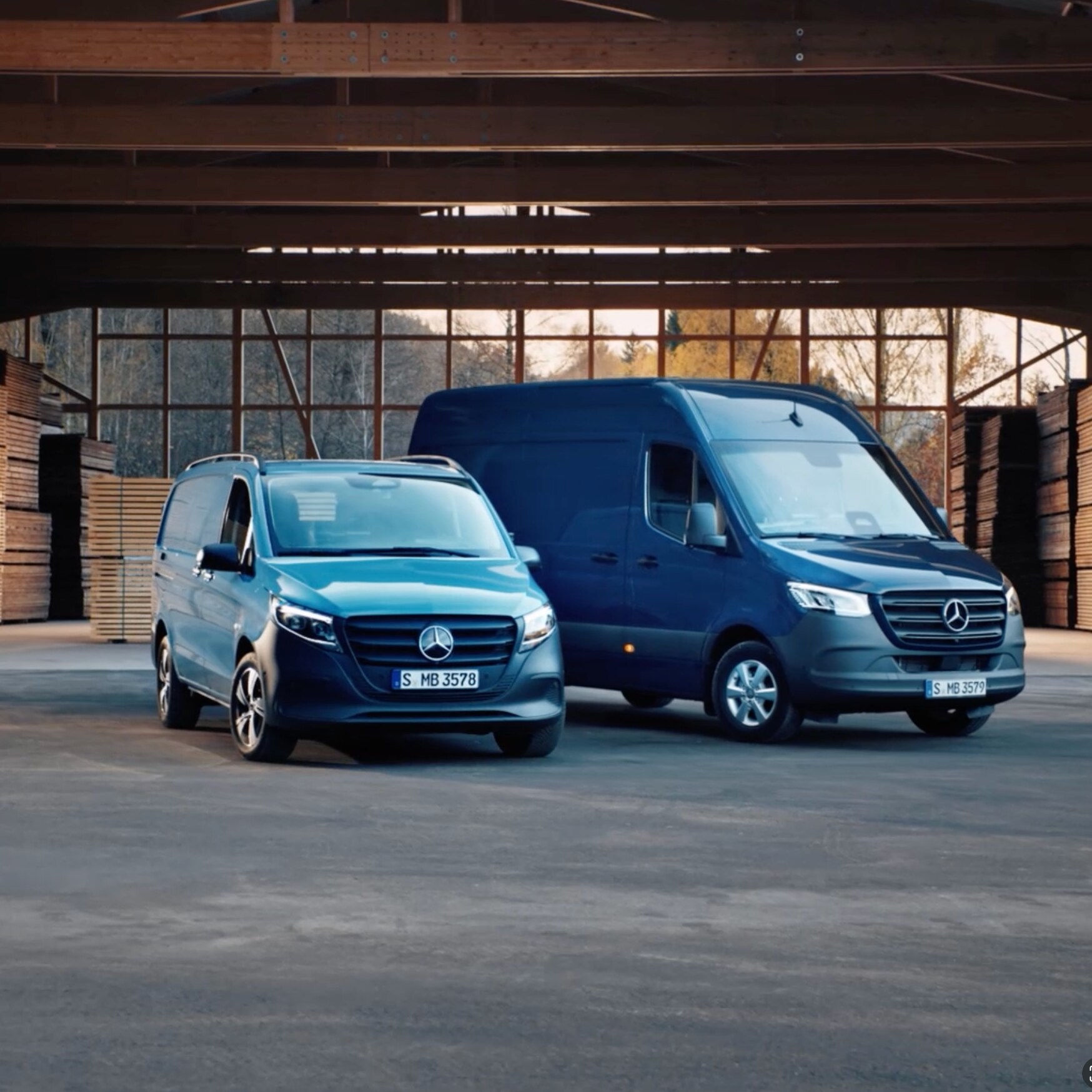 Zwei verschiedene Transportermodelle von Mercedes-Benz stehen in einer Lagerhalle.