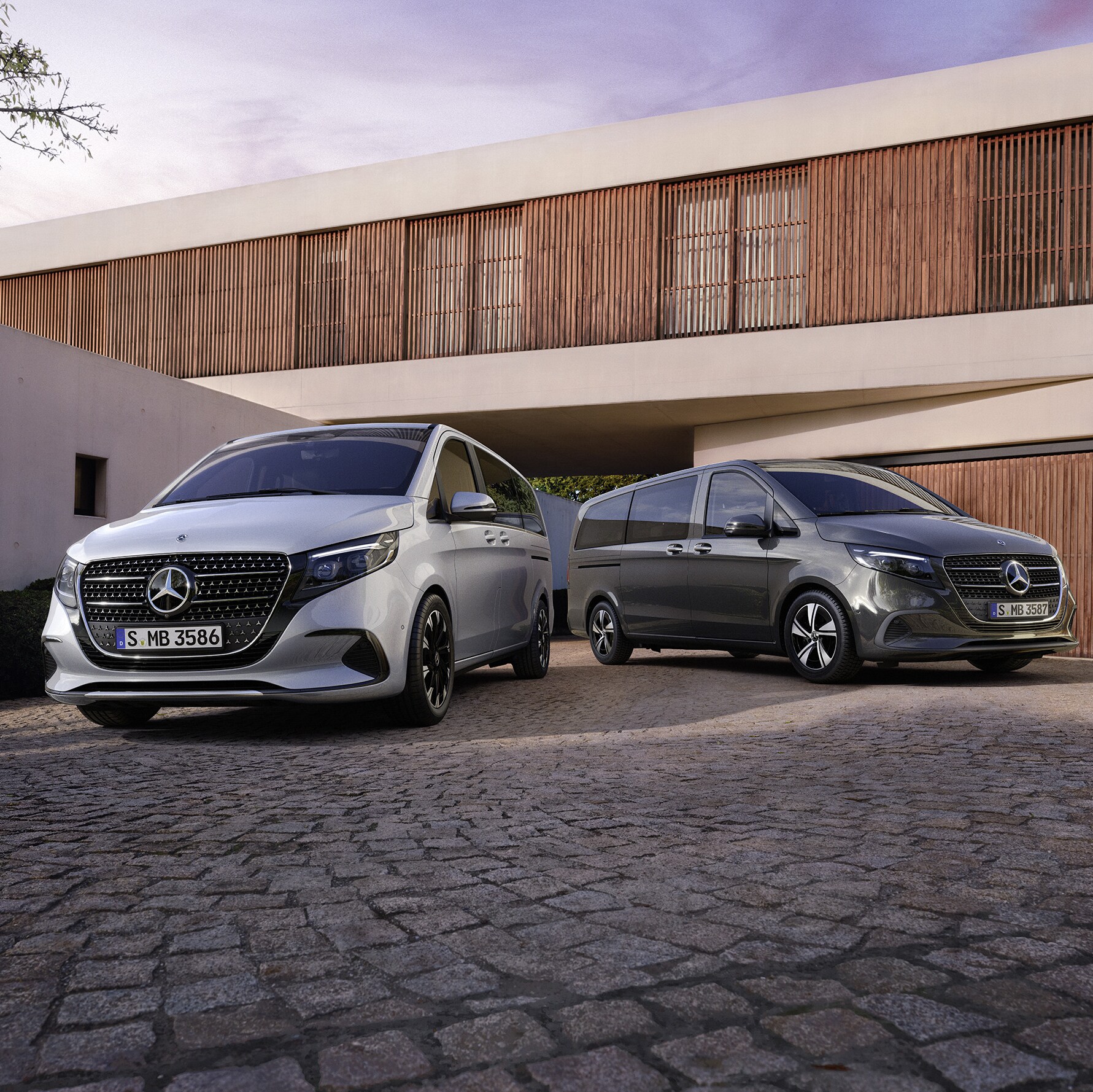Zwei Mercedes-Benz V-Klassen parken vor einem mordernen Haus mit Garage.