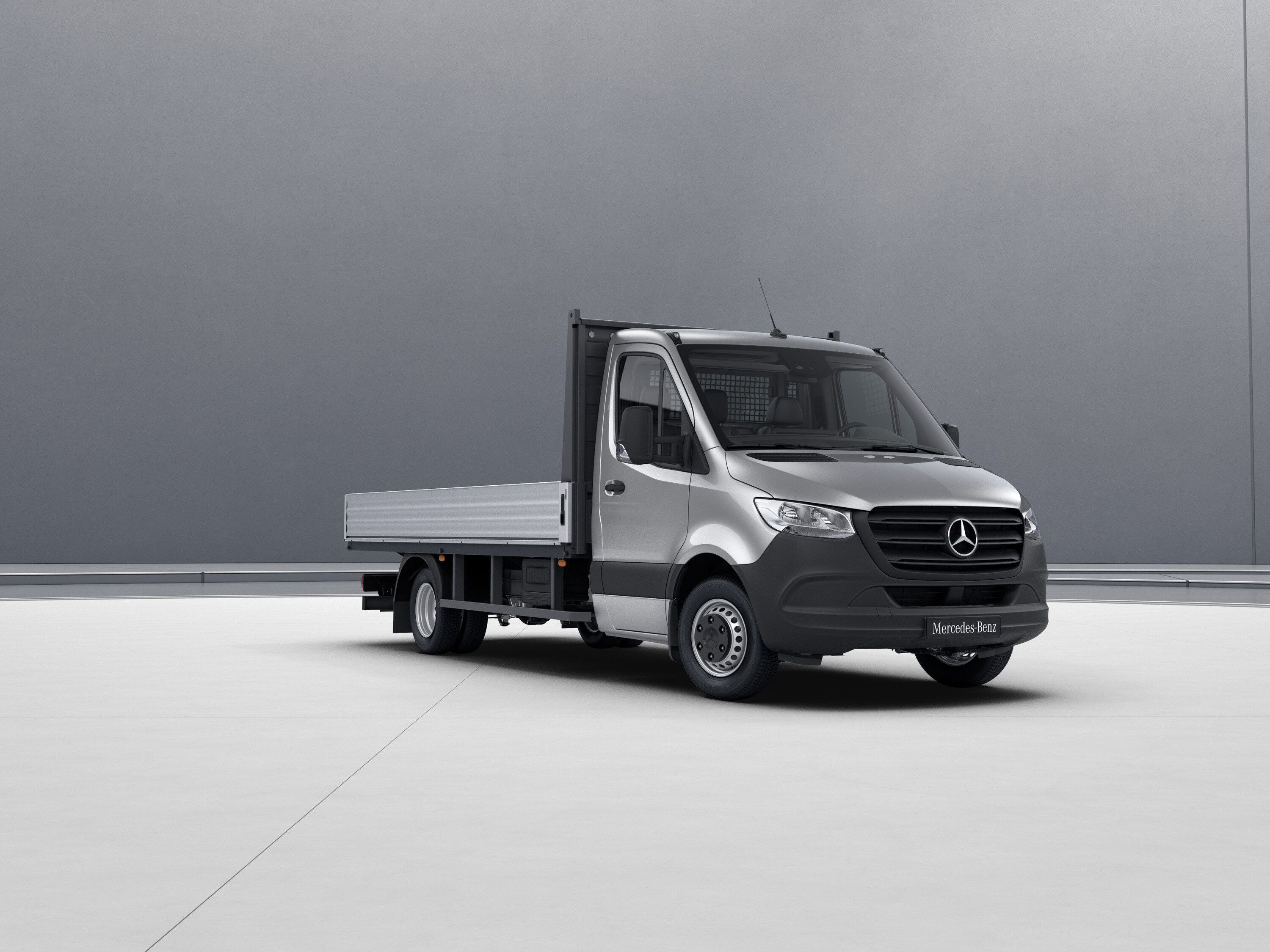 Eine silberne Sprinter Pritsche von Mercedes-Benz steht vor einem neutralen, grauen Grund.