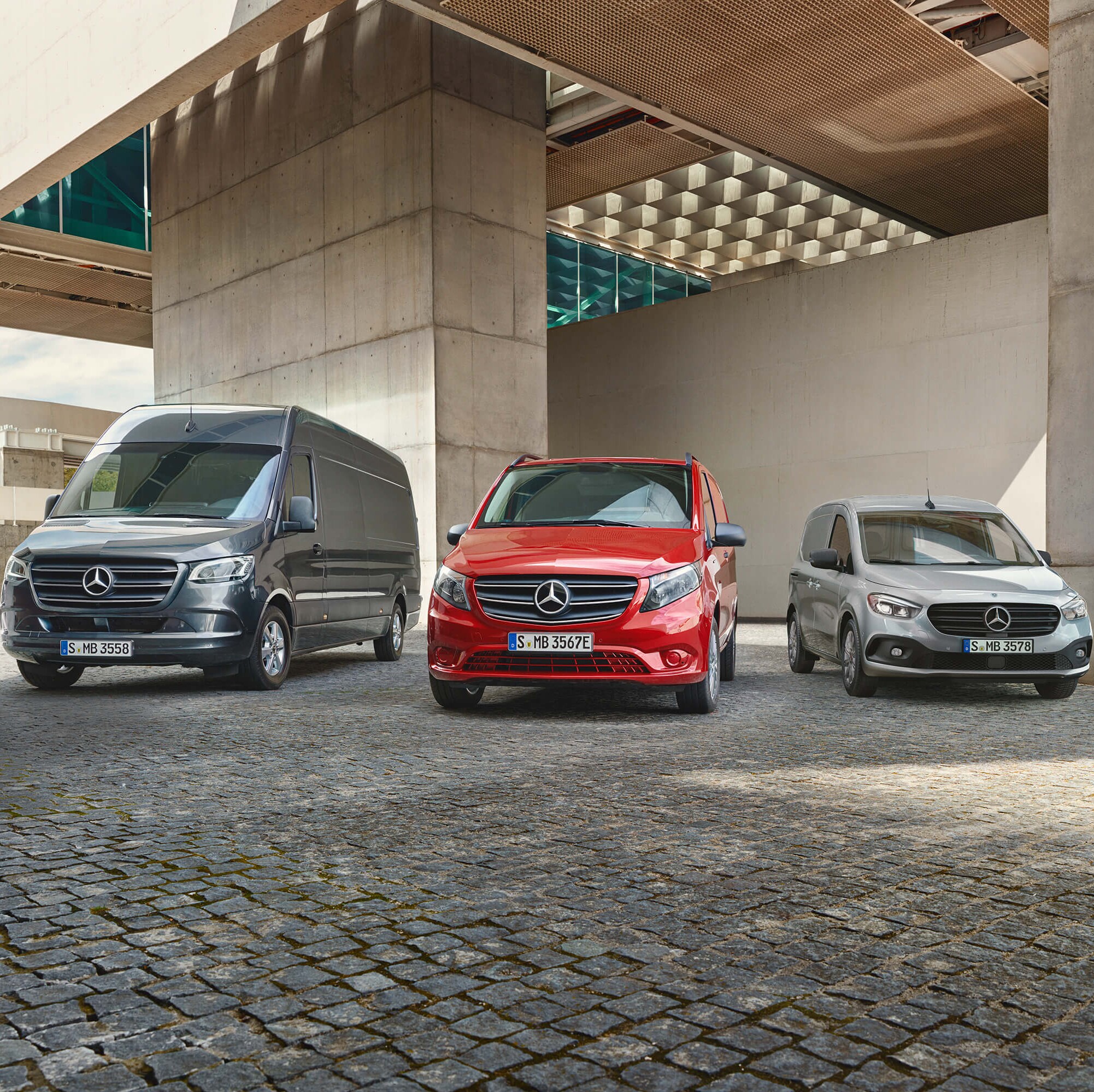 Drei Mercedes-Benz Transporter aus Frontansicht stehen unter einer Beton Brücke.