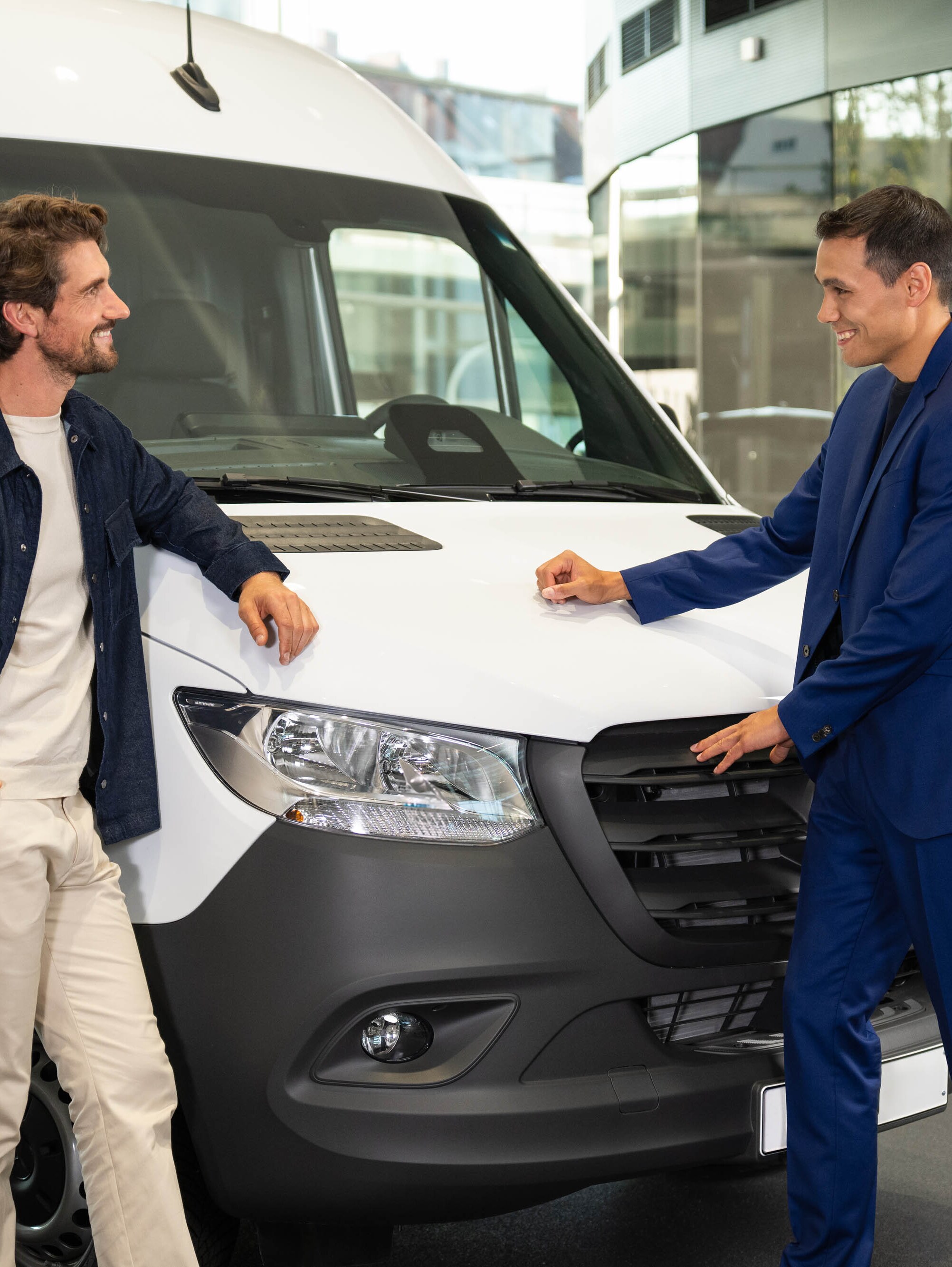 Zwei Personen lächeln und unterhalten sich vor einem Mercedes-Benz Transporter.