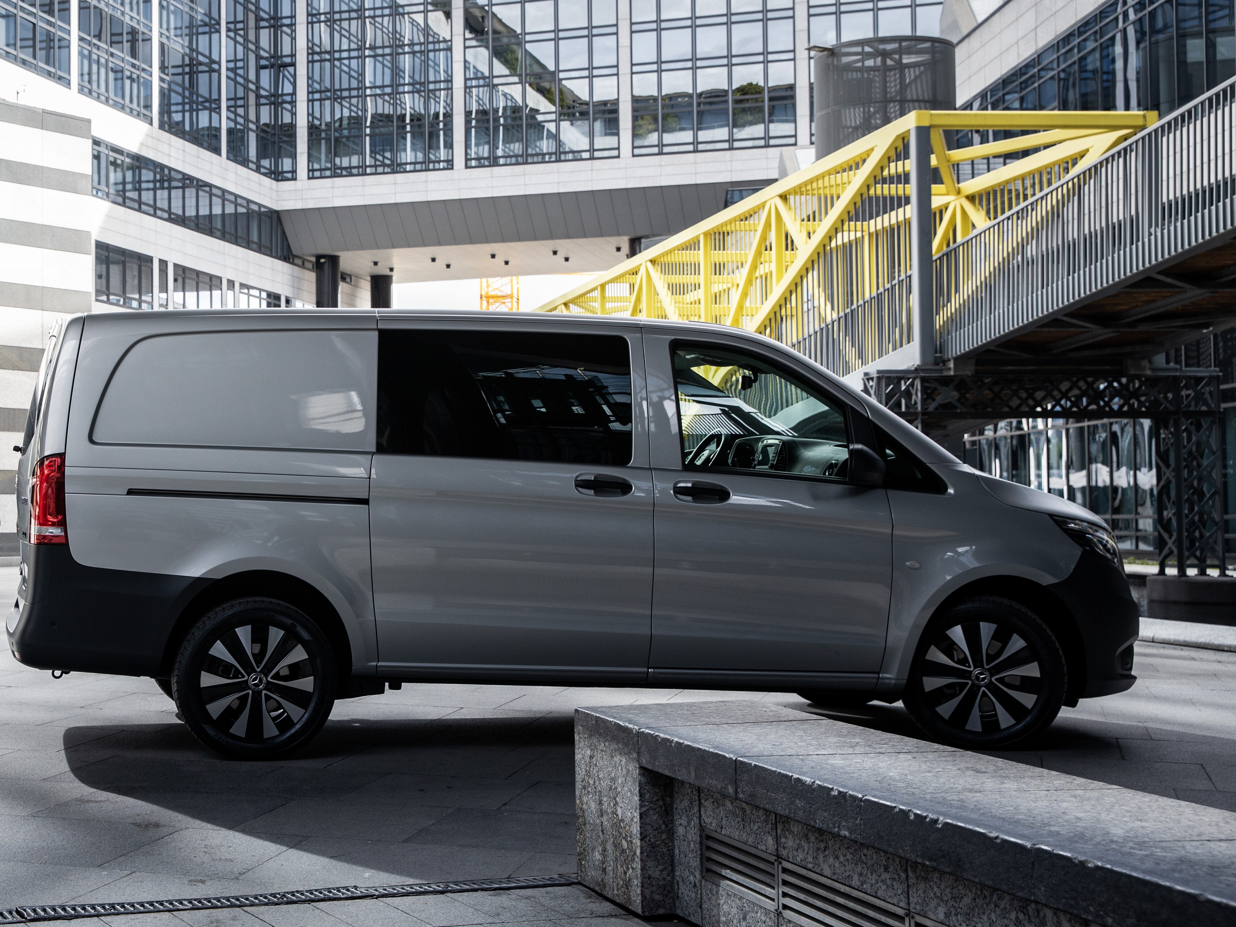 Zwei Mercedes-Benz Transporter Kastenwagen die voreinander in einem Innenhof stehen. 