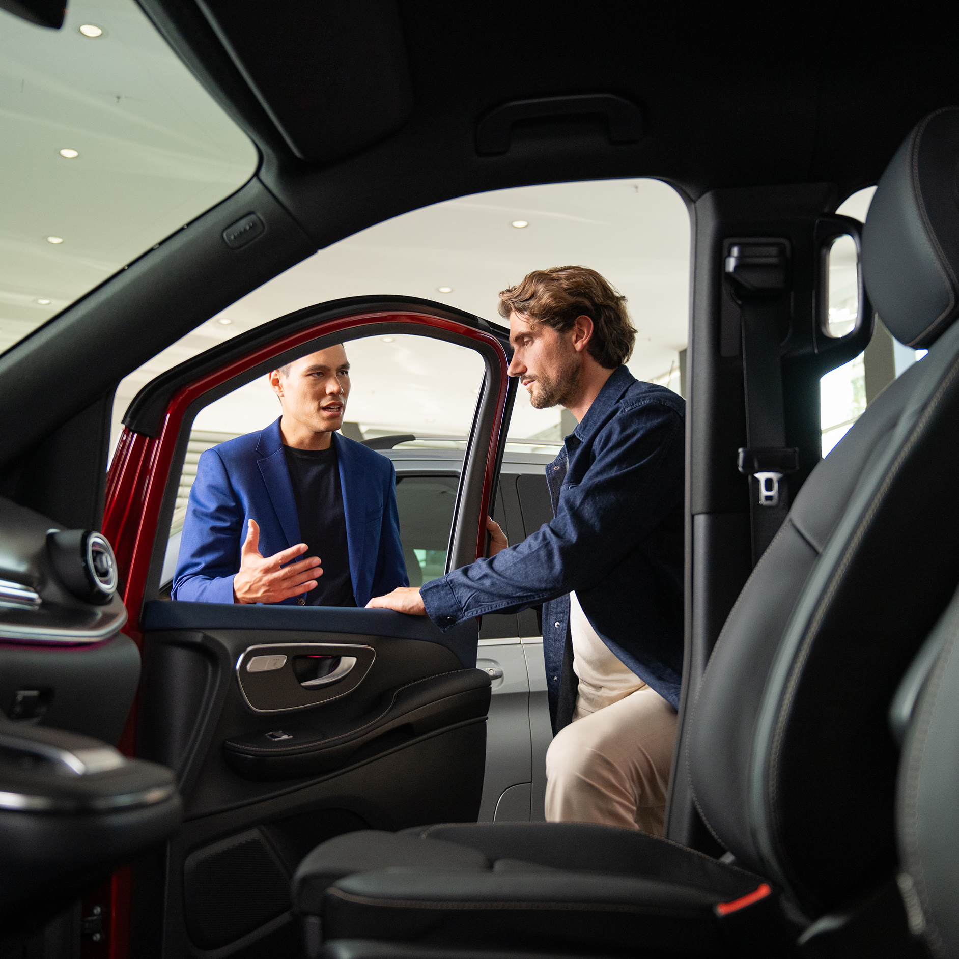 Mercedes-Benz Kontakt Leasing, Finanzierung und Versicherung Innenansicht eines Mercedes-Benz Transporters mit Blick auf zwei sich unterhaltenden Personen an der geöffneten Tür.