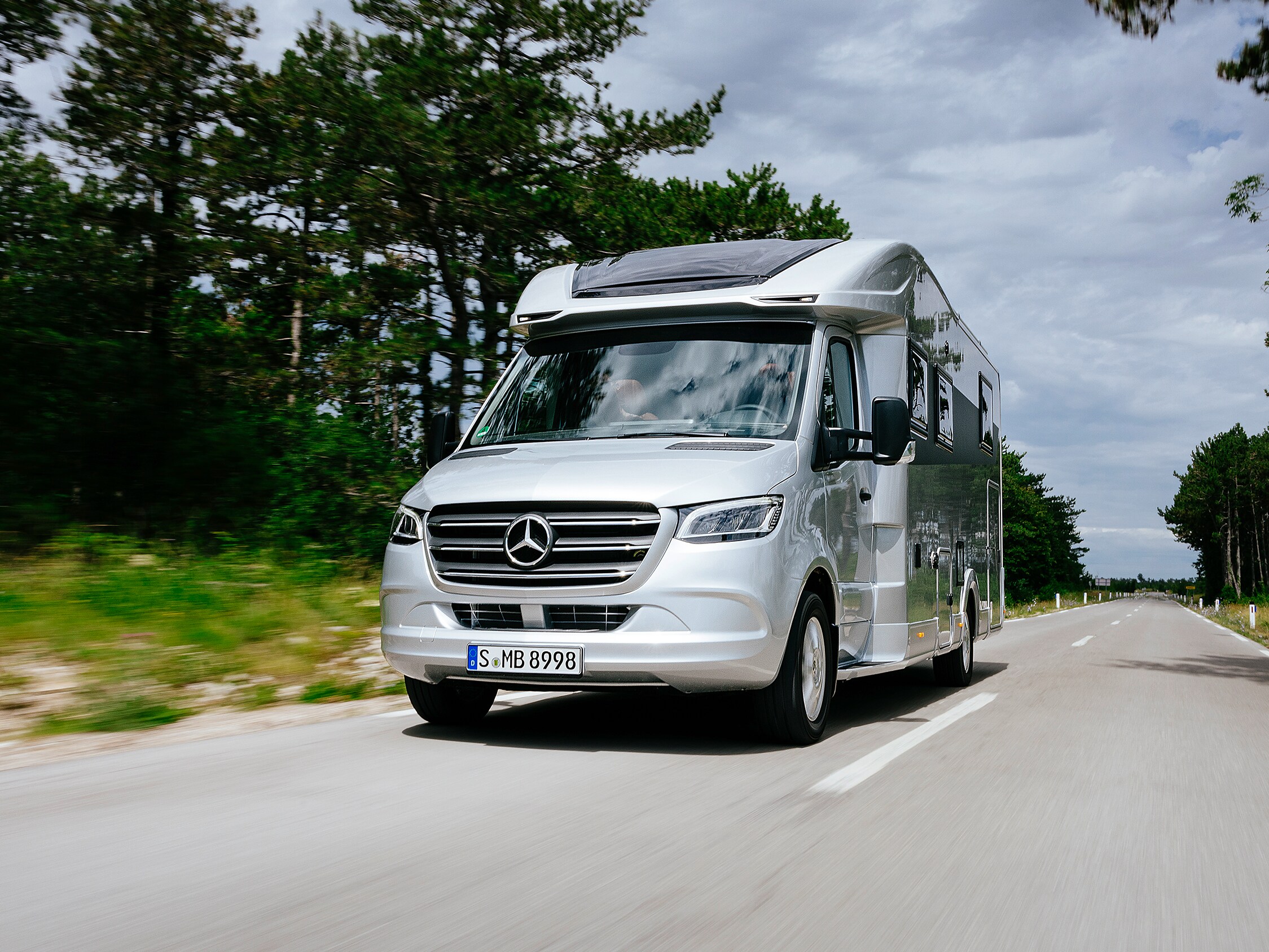 Ein Sprinter Fahrgestell als Basis mit einem gezeichneten Reisemobil Aufbau steht in einer Fabrikhalle.