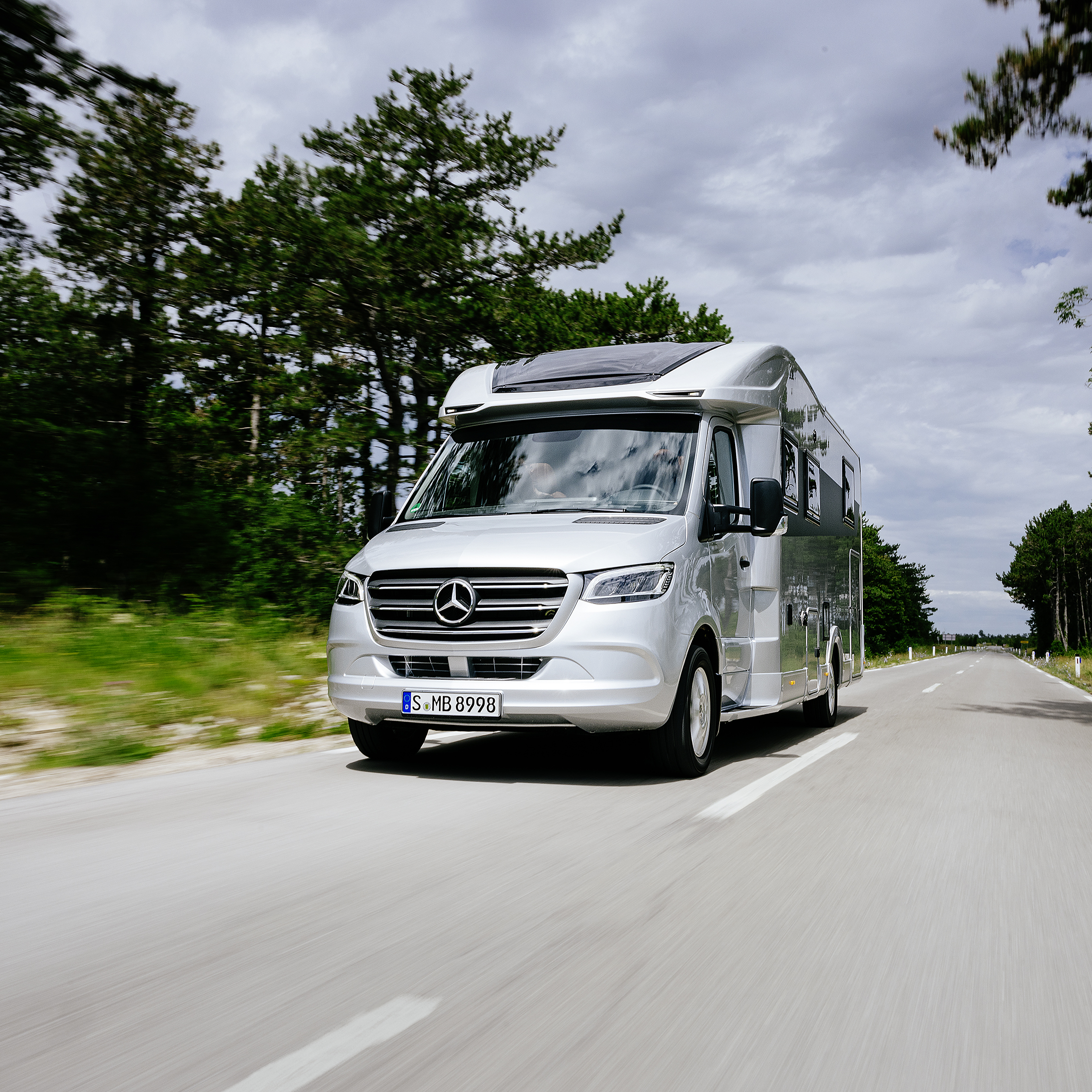 Der Sprinter – Variantenvielfalt für Ihre Reisemobil-Basis. Ein Sprinter Fahrgestell als Basis mit einem gezeichneten Reisemobil Aufbau steht in einer Fabrikhalle.