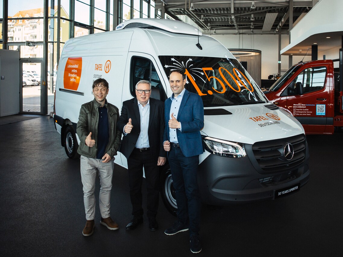 Drei Personen stehen vor einem Mercedes-Benz Sprinter feierlich zu einer offiziellen Übergabe.