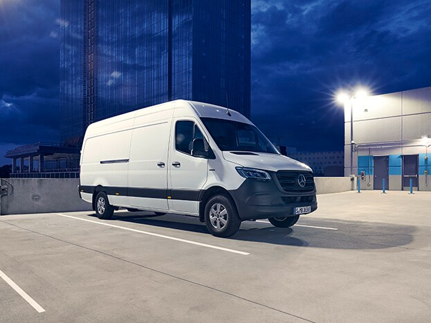 Ein eSprinter Kastenwagen parkt vor einem blauen Hochaus.