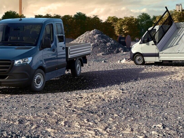 Das Sprinter Pritschenfahrzeug auf einer Baustelle mit Schotterboden und einem Schuttberg im Hintergrund. 