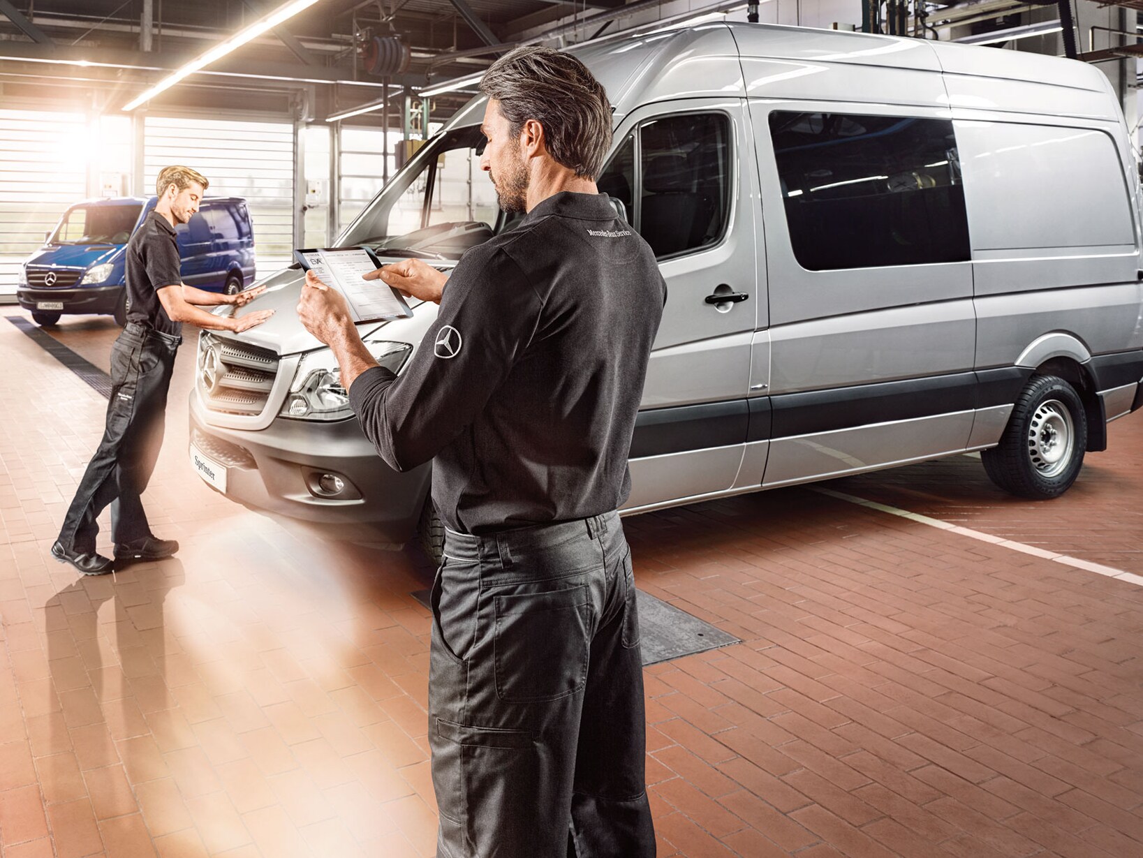 Zwei Personen halten Checklisten in den Händen und prüfen einen Mercedes-Benz Transporter in einer Fabrikhalle.