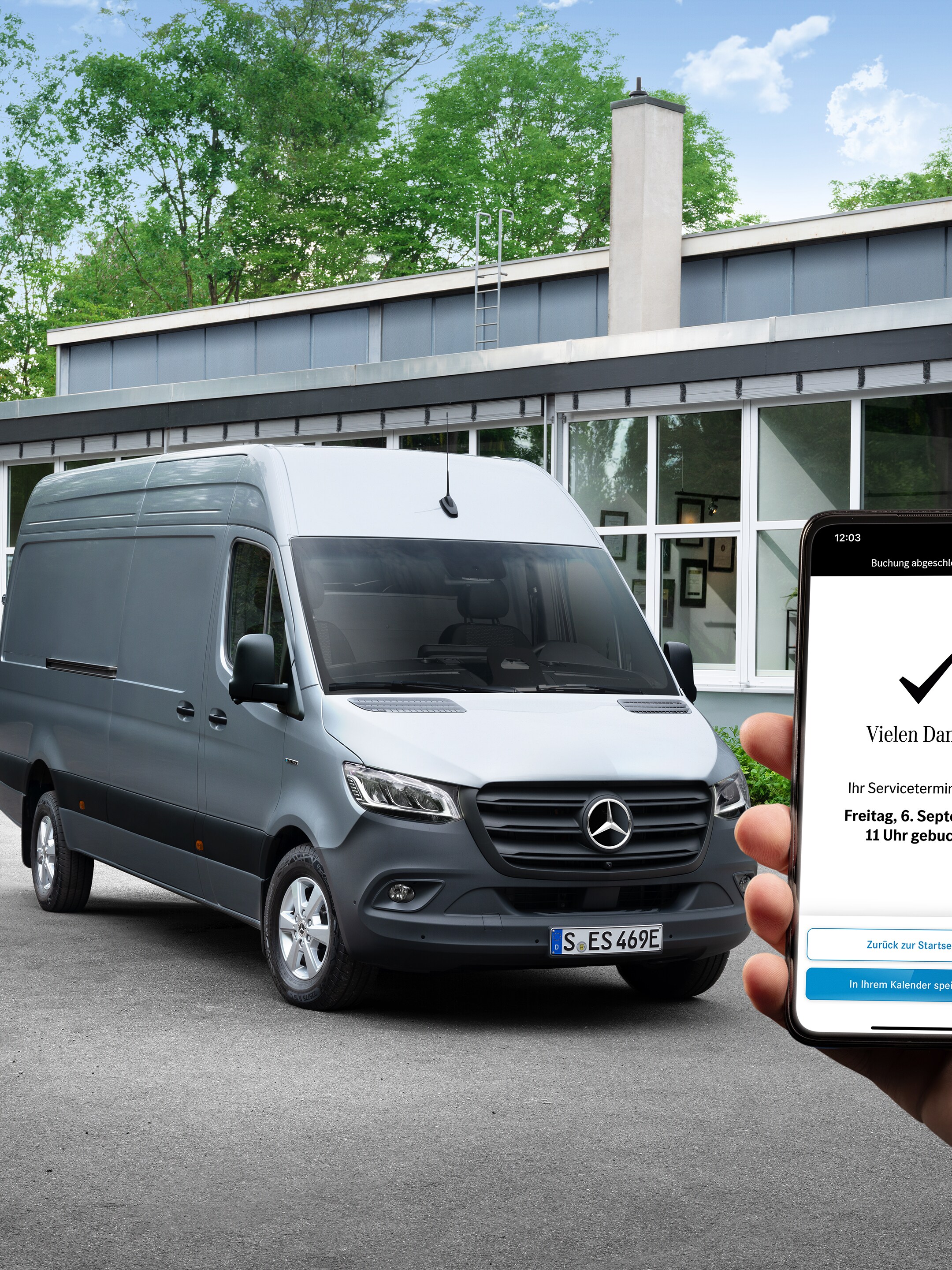 Ein Hand hält ein Smartphone in den Händen. Im Hintergrund steht ein Mercedes-Benz Transporter.