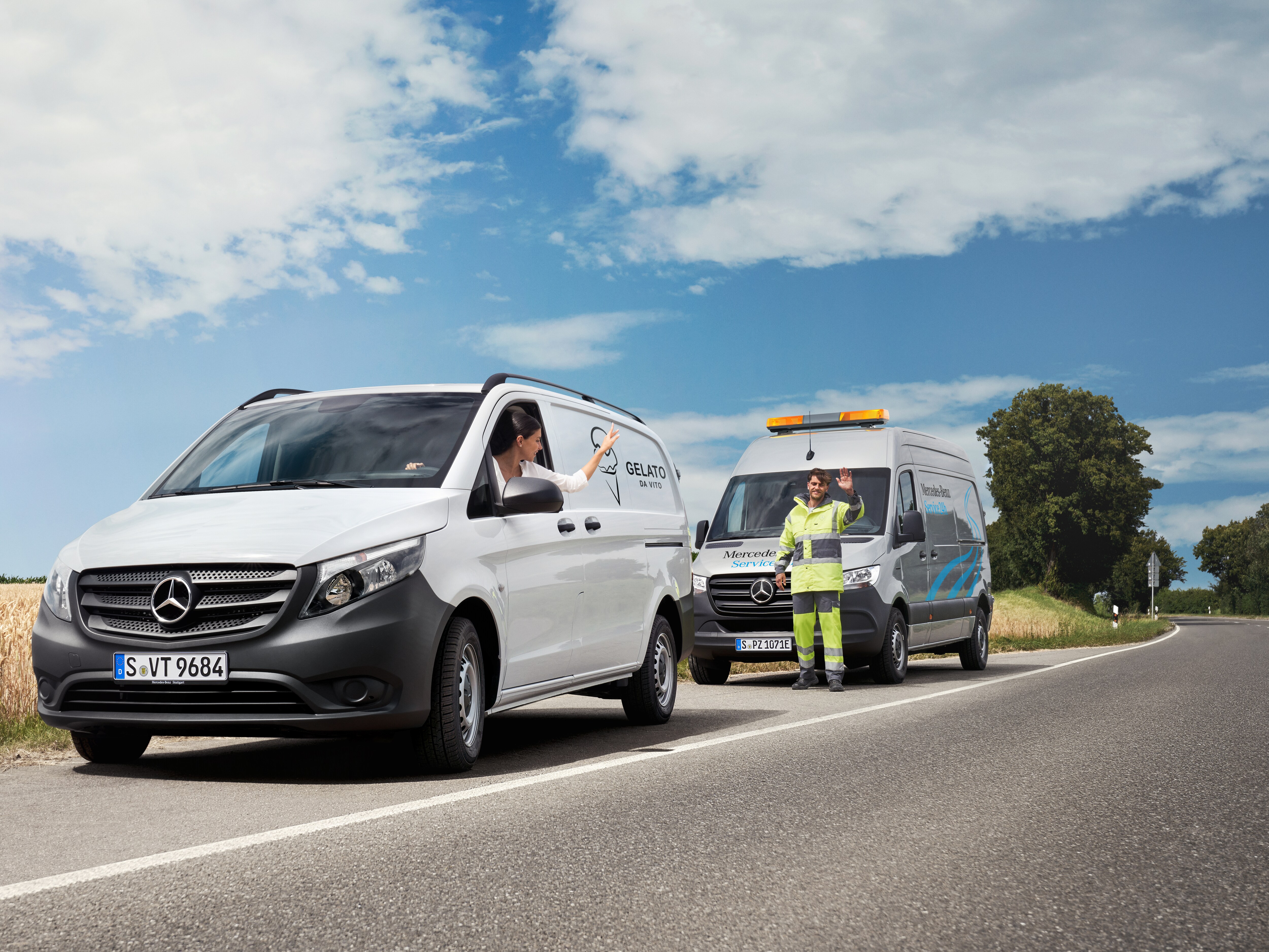 Ein Mercedes-Benz Vito und ein Sprinter stehend an der Straßenseite. Ein Service Mitarbeiter winkt.