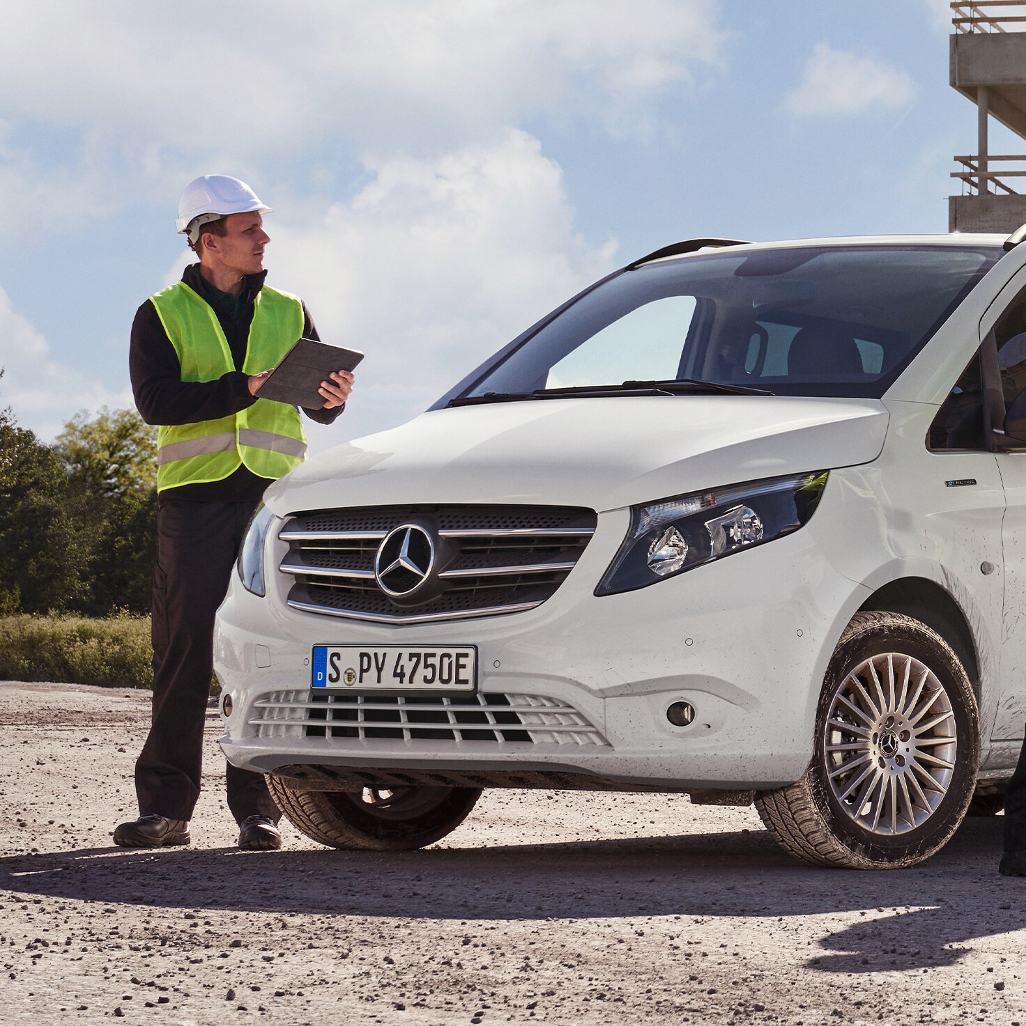 Drei Bauarbeiter mit Sicherheitshelm stehen um einen weißen Transporter von Mercedes-Benz herum.