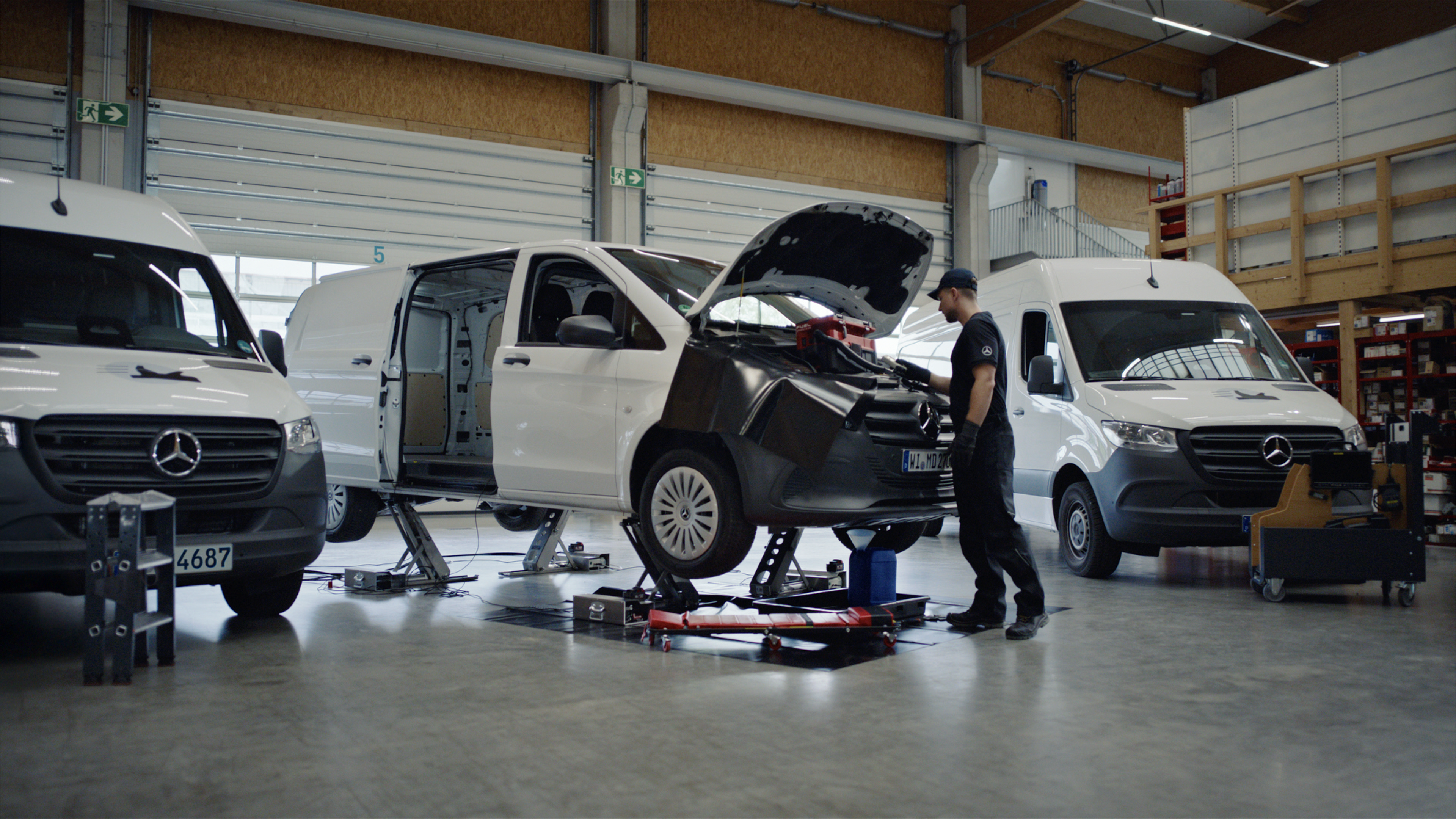 Mobile Service | Mercedes-Benz Transporter. Ein Techniker repariert auf einem Rollbrett liegend einen weißen Mercedes-Benz Vito.