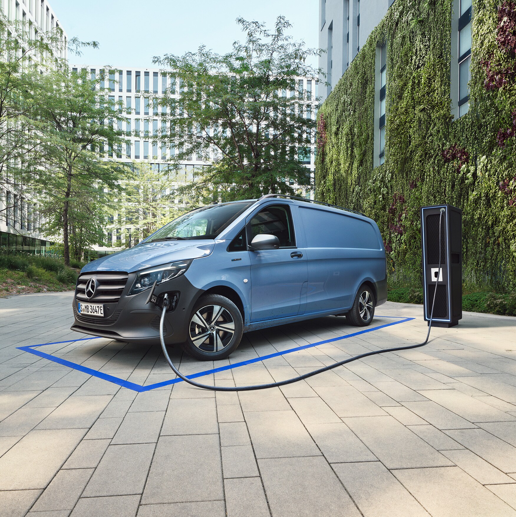 Ein vollelektrischer Transporter von Mercedes-Benz steht an einer Ladesäule.