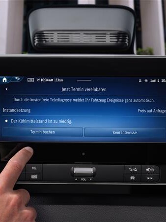 Finger tippt im Auto auf den Bildschirm, um einen Termin über die Mercedes-Benz Service App zu buchen.