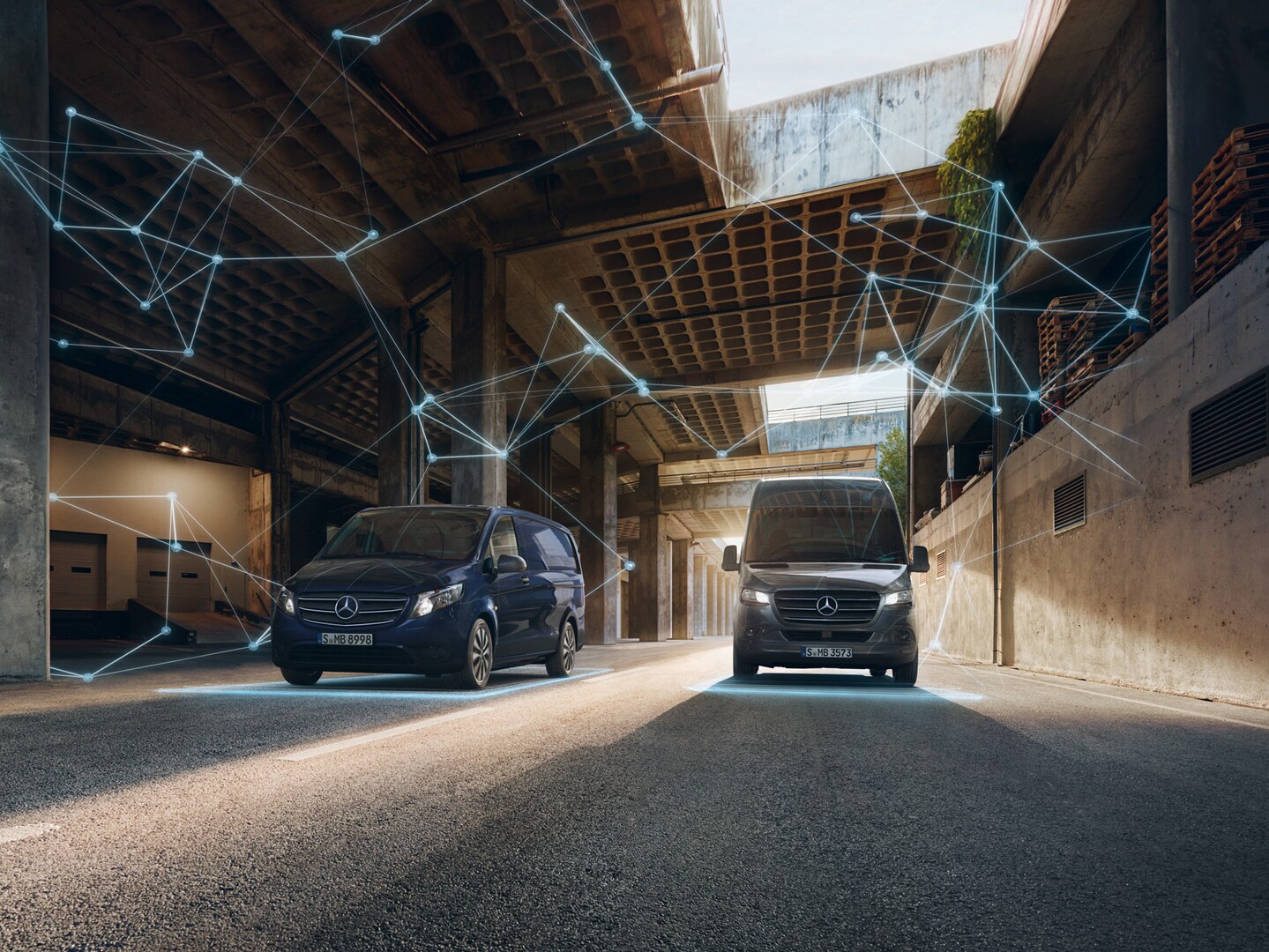 Zwei Mercedes-Benz Transporter in Fronansicht stehen in einer Fabrikhalle. Leuchtende Punkte und Streifen symbolisieren die digitale Produktwelt.