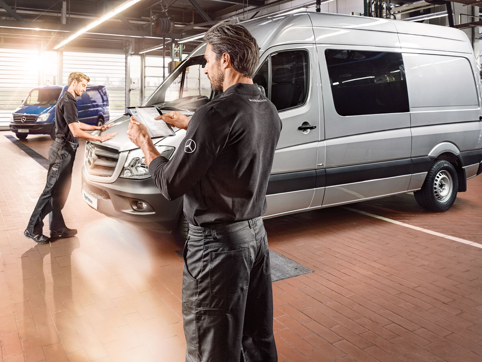 Zwei Personen halten Checklisten in den Händen und prüfen einen Mercedes-Benz Transporter in einer Fabrikhalle.
