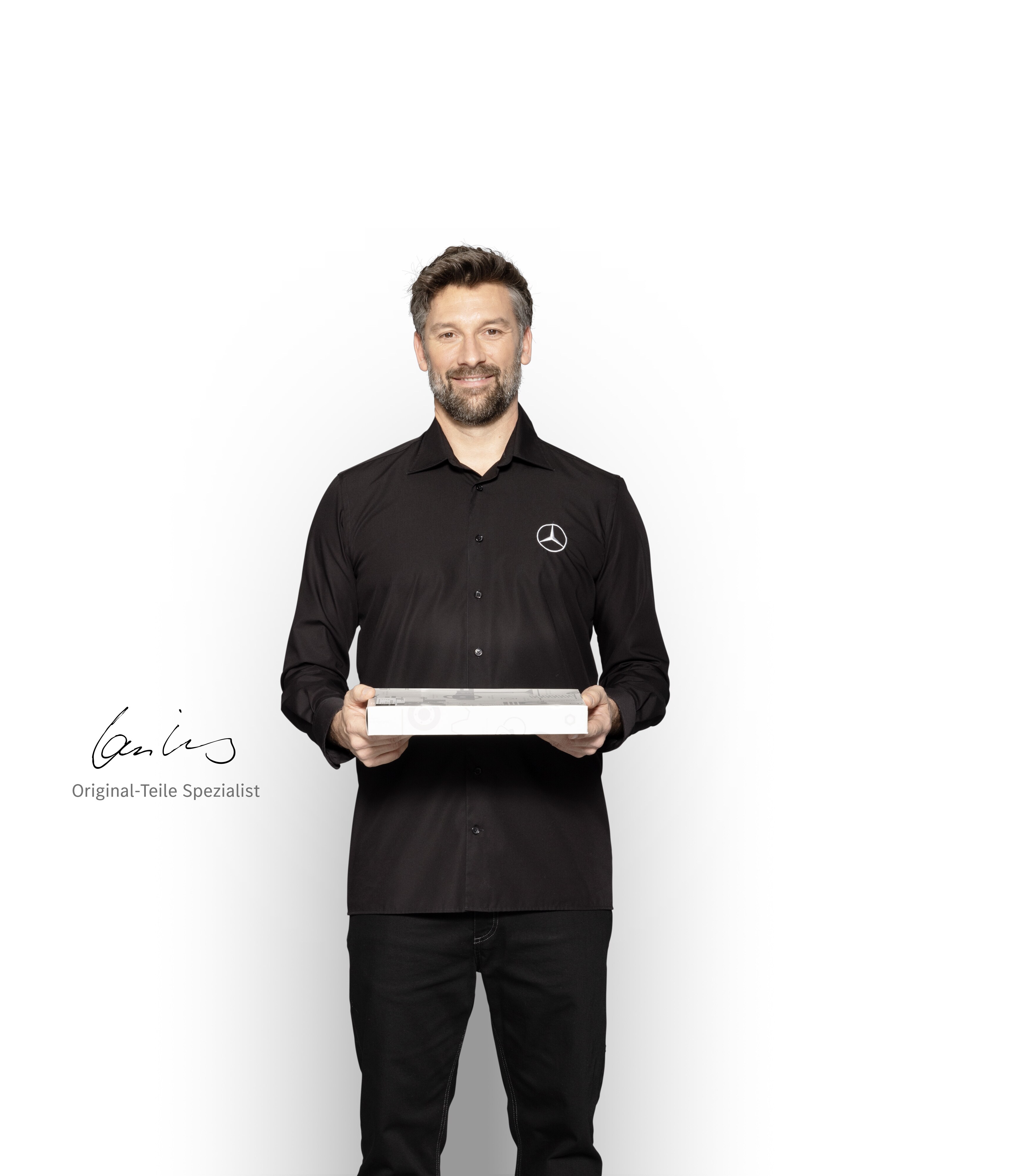 Mercedes-Benz Techniker mit einer Box in der Hand, um Mercedes-Benz Original-Teile zu zeigen.