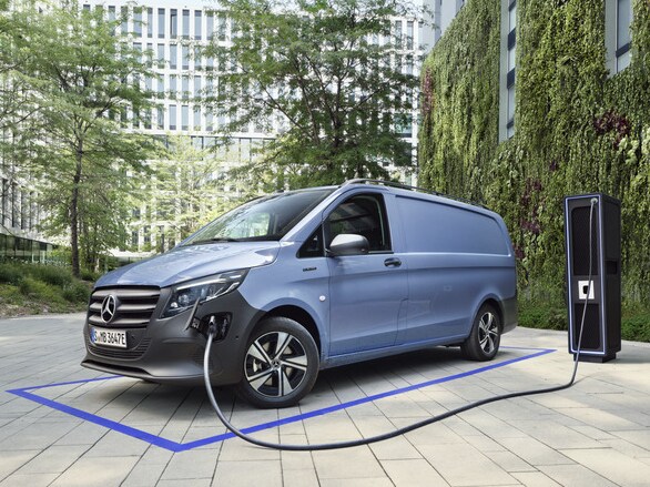 Ein blauer eCitan von Mercedes-Benz wird zwischen hohen Gebäuden an einer Ladesäule geladen.