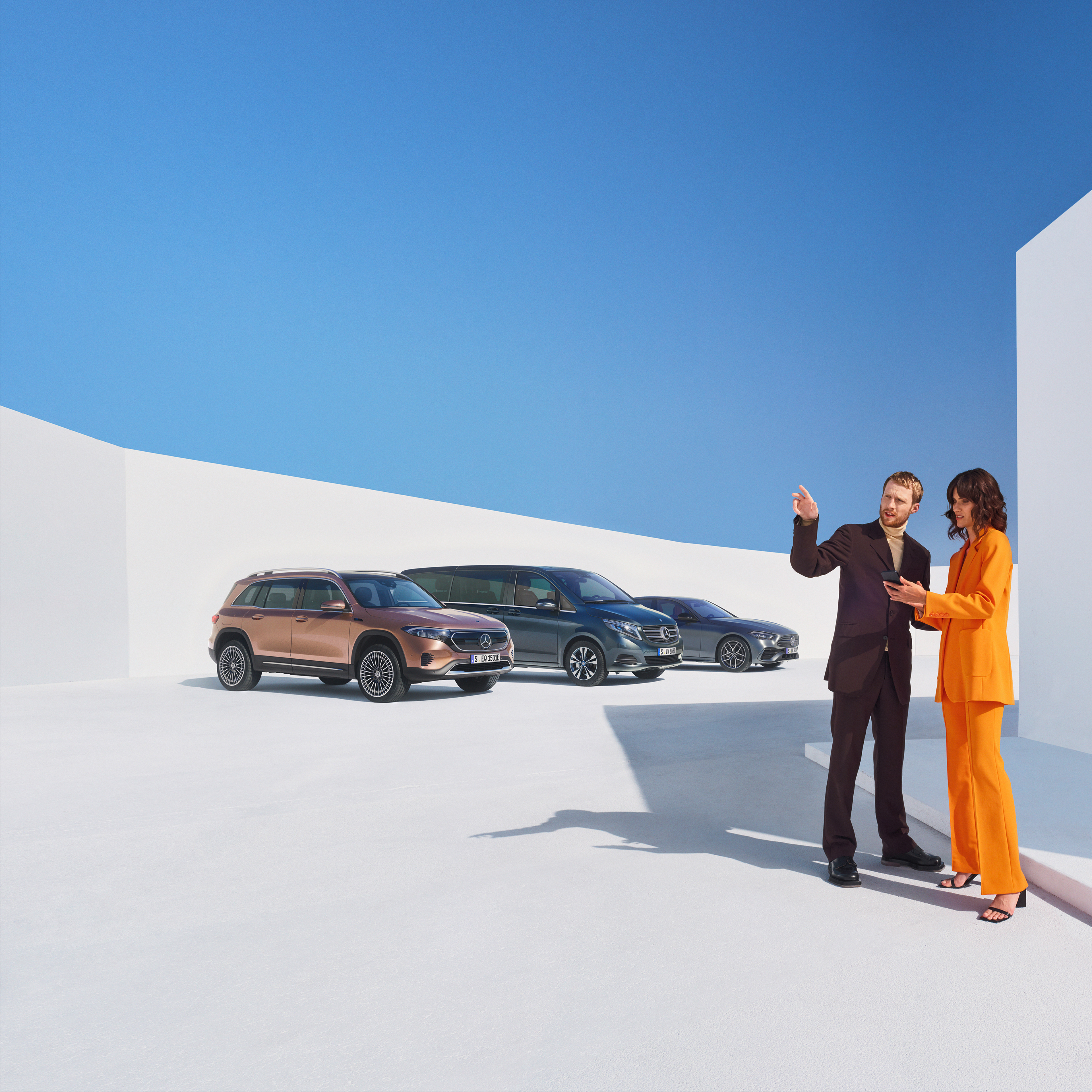 Business | Digitale Extras Zwei Personen unterhalten sich über die Digitalen Extras für Geschäftskunden. Im Hintergrund sind drei Mercedes-Benz Fahrzeuge zu sehen.